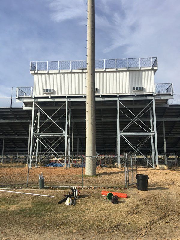 Metal stadium structure with press box, light pole, and bleachers.
