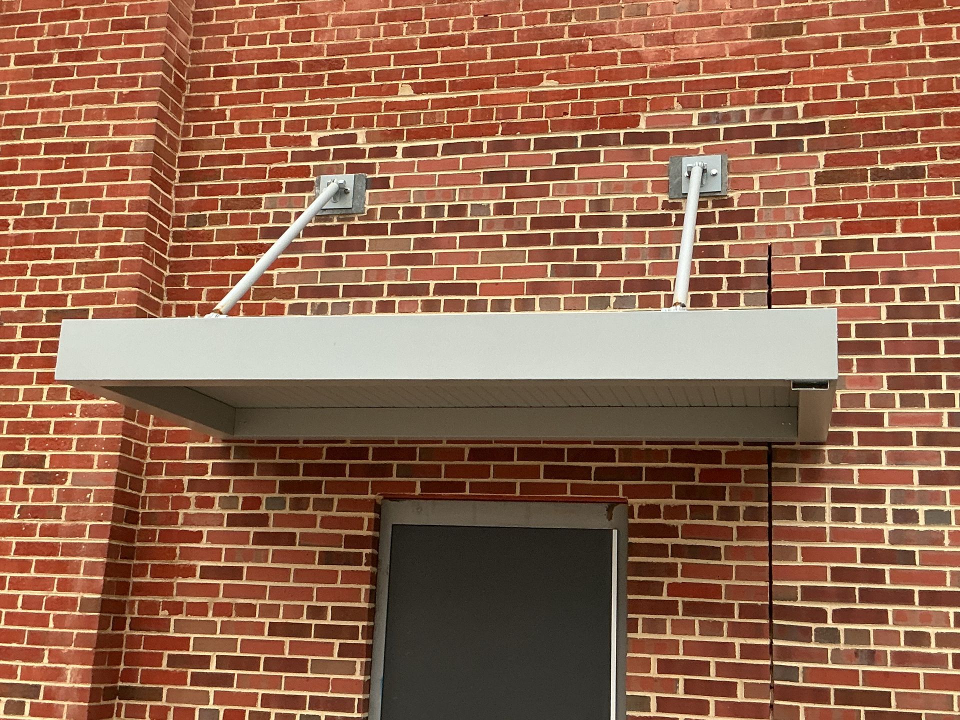 Exterior of a building with a metal awning and a walkway. Cloudy sky above.