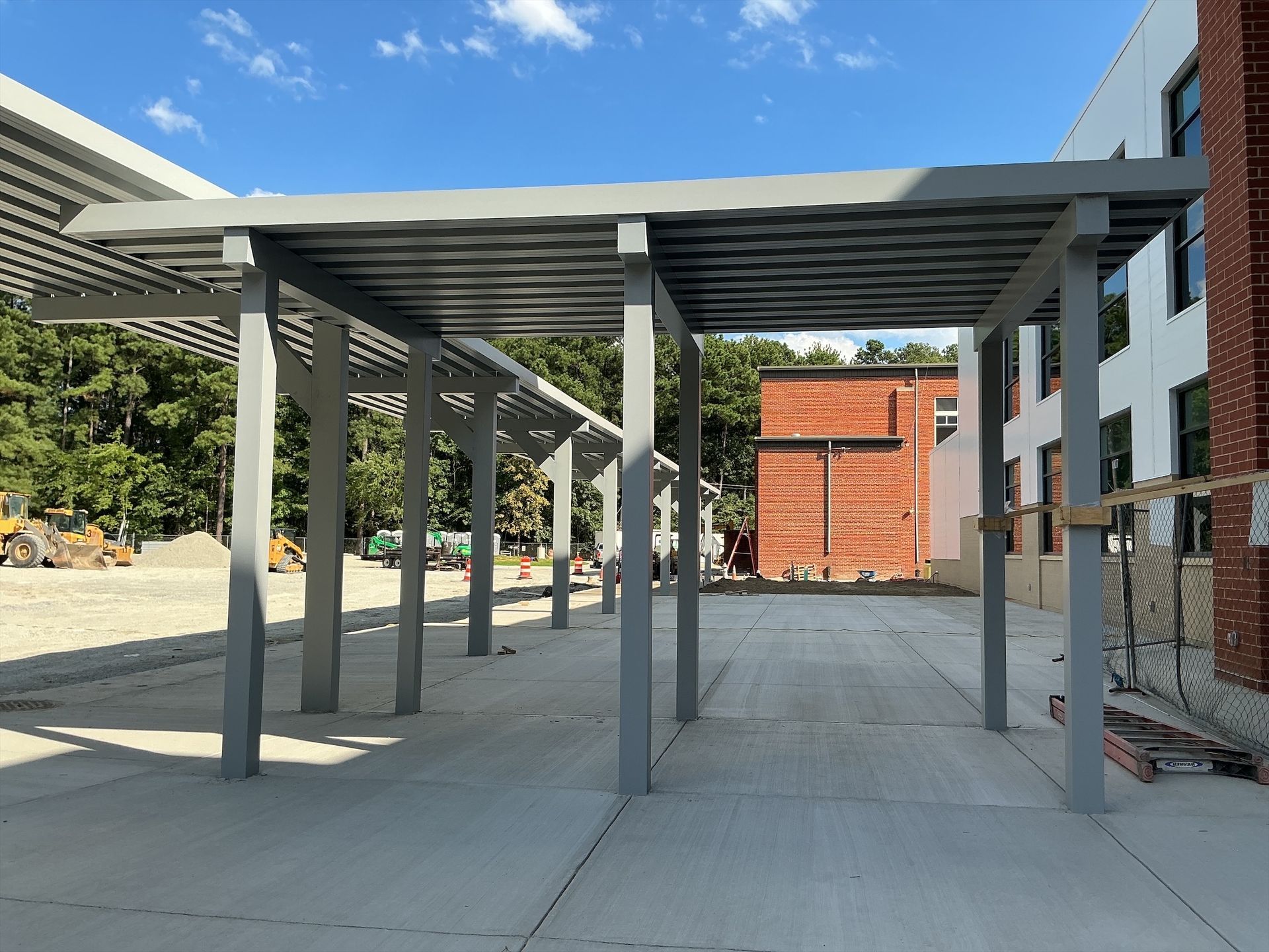 Exterior of a building with a metal awning and a walkway. Cloudy sky above.