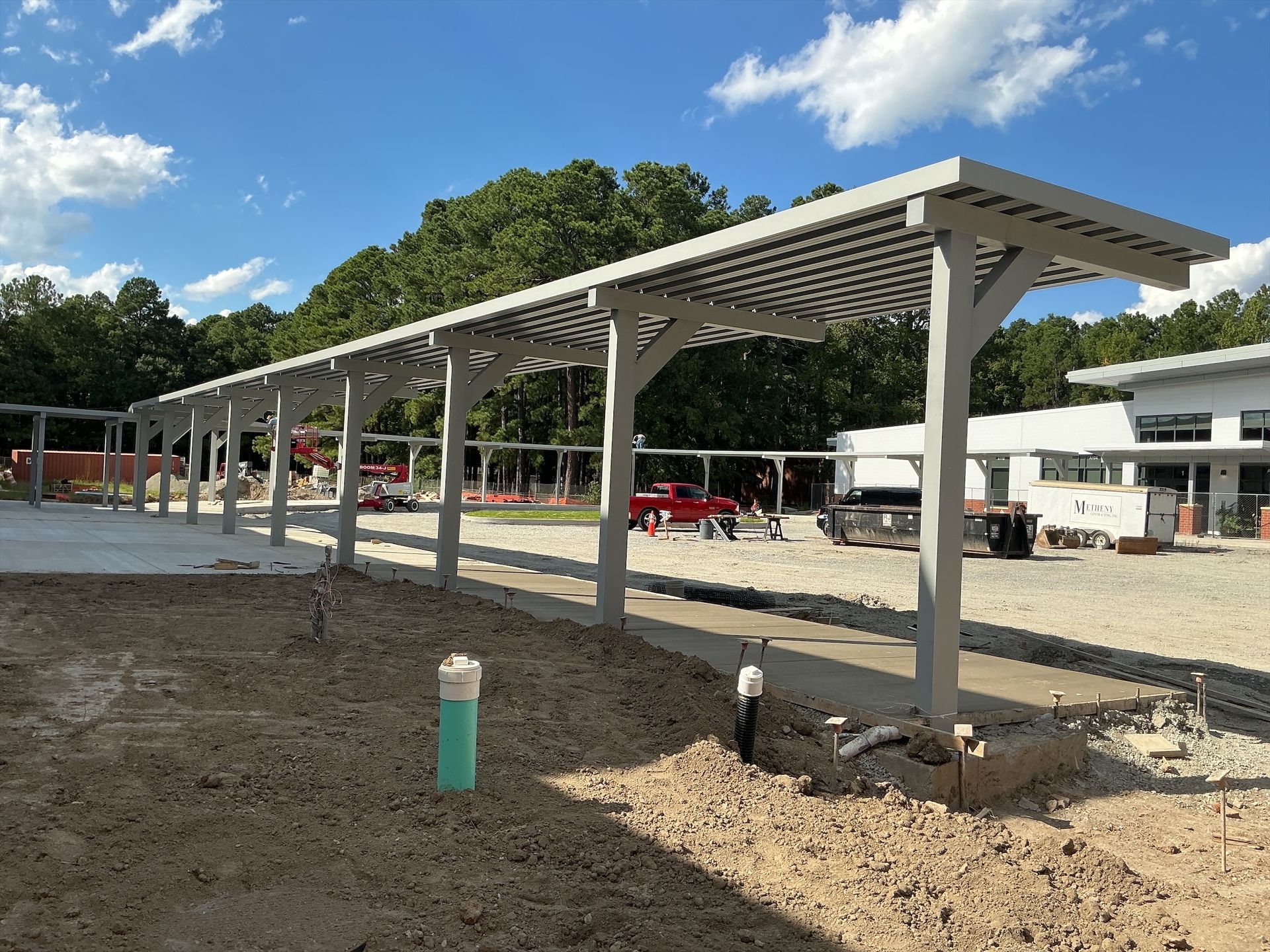 Exterior of a building with a metal awning and a walkway. Cloudy sky above.