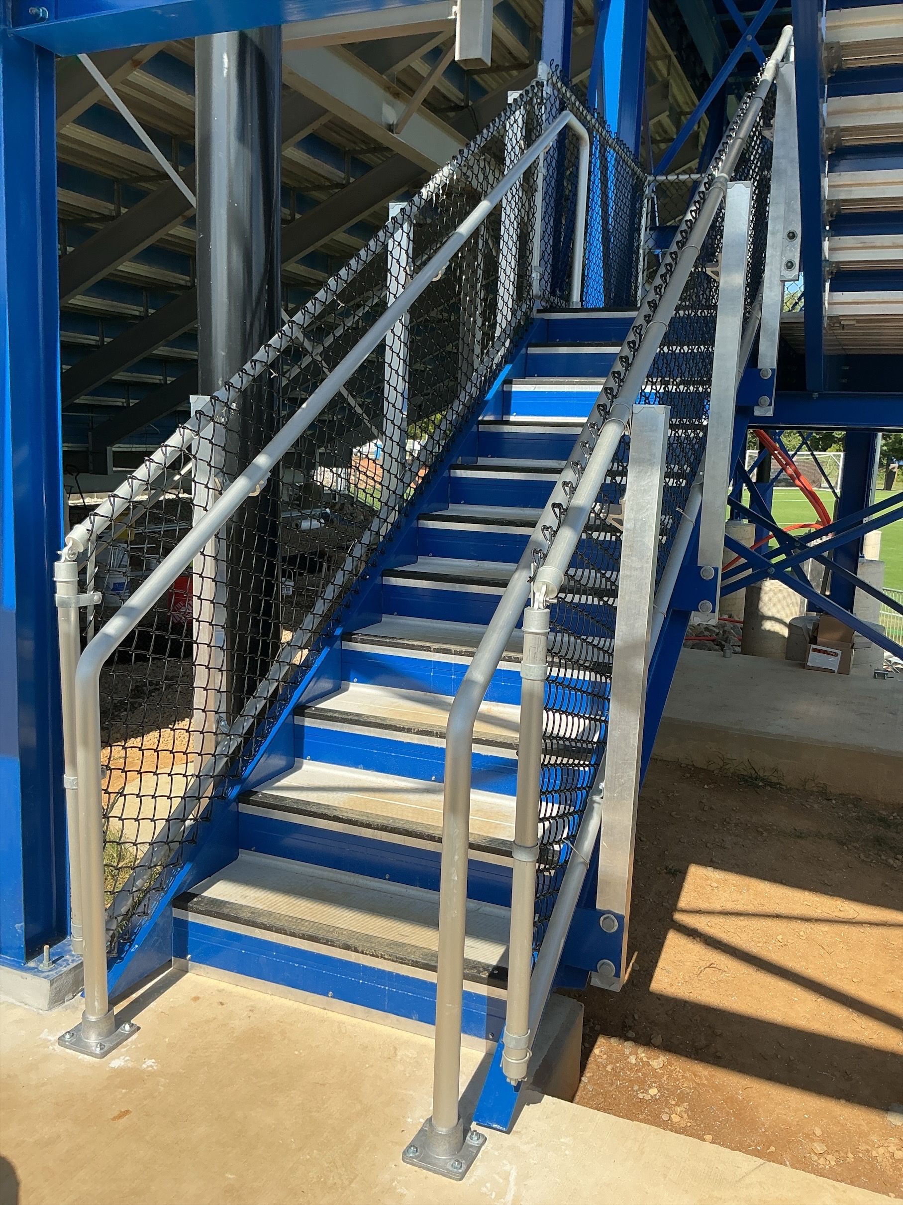 Blue metal staircase with silver railings and steps, outdoors.