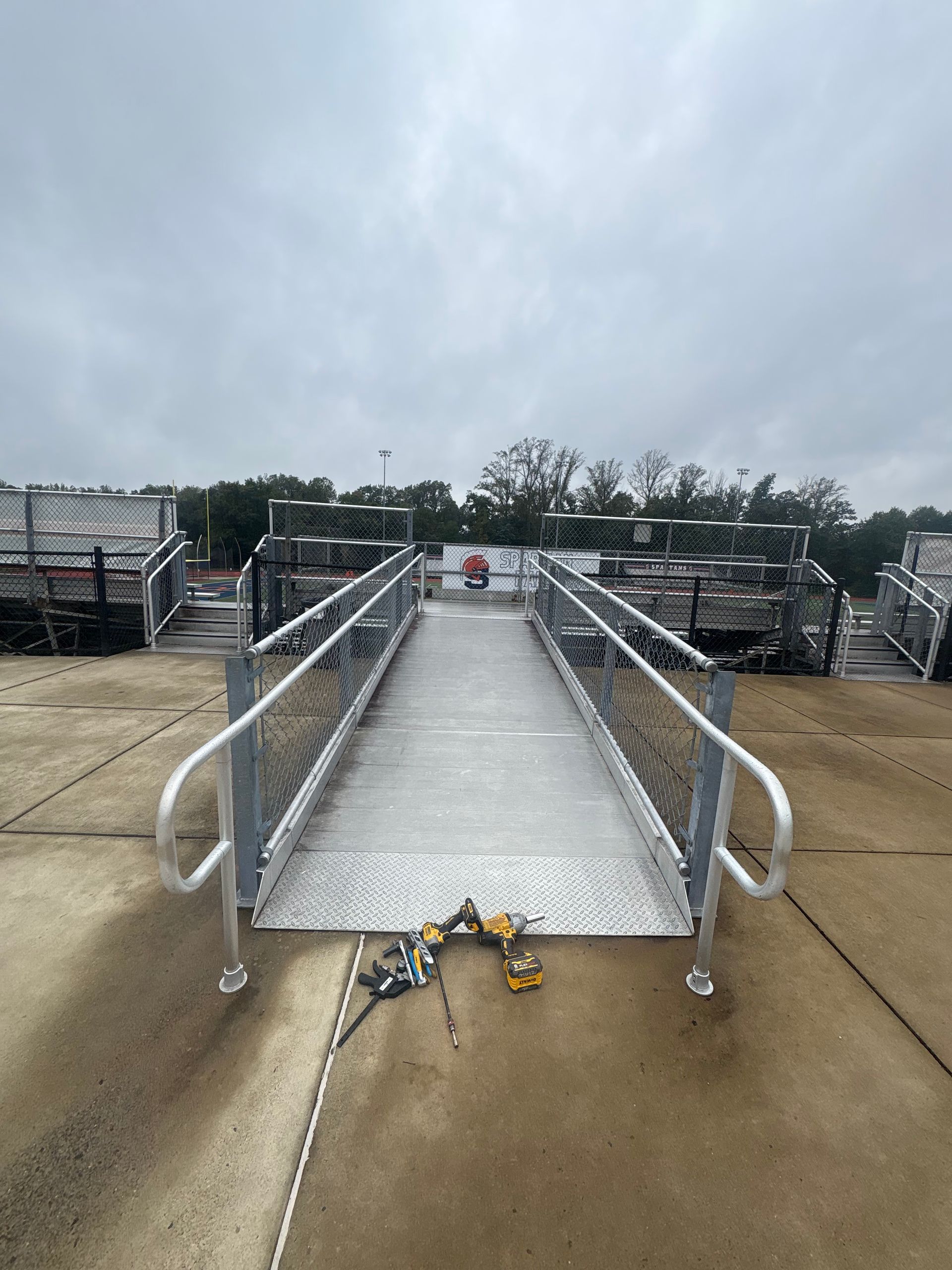 A metal ramp with railings leading to a dock, likely for boat access. Overcast sky.