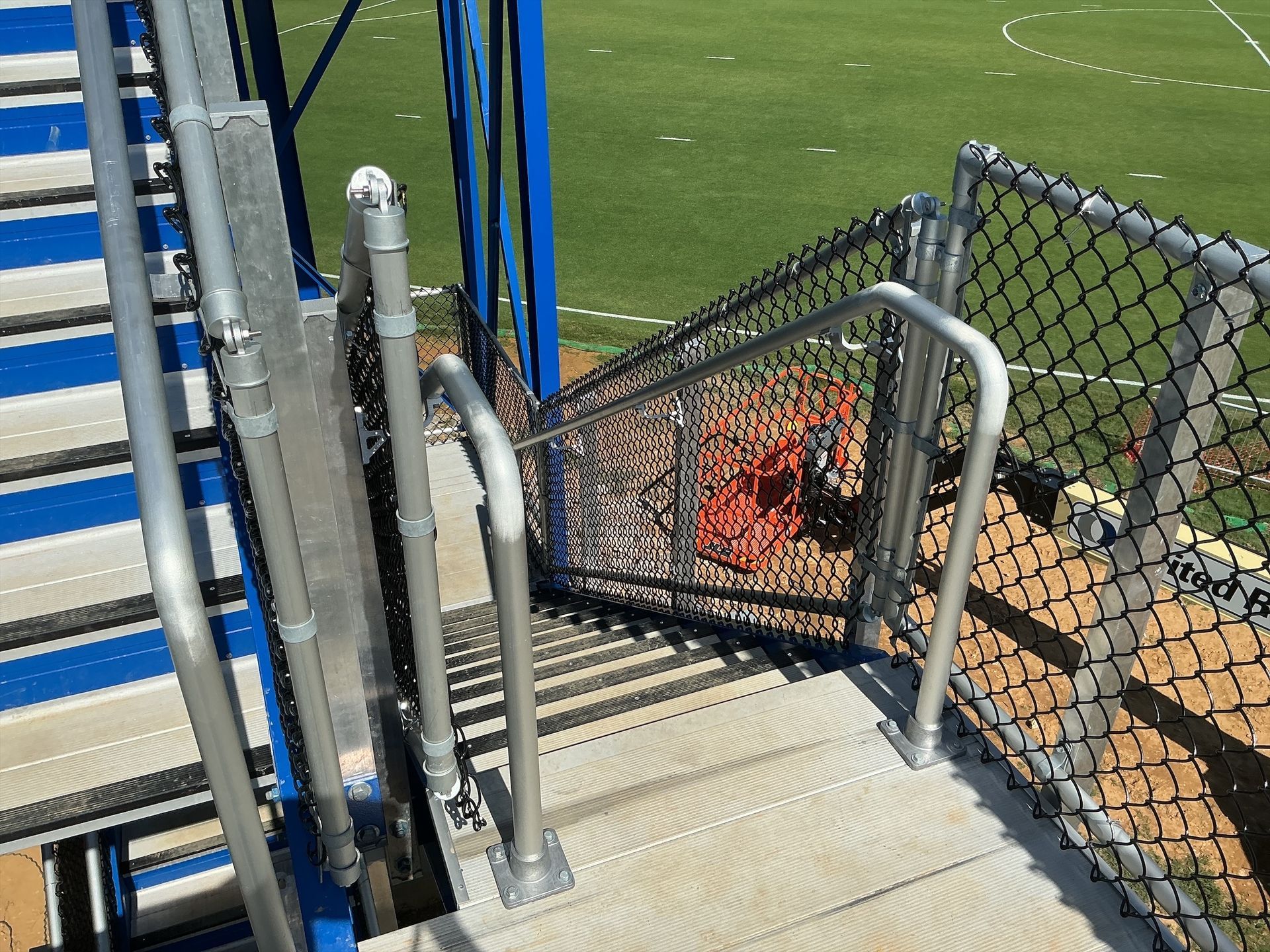 Stairway with blue accents and metal railings leads down from a blue structure. Chain-link fence surrounds the area.