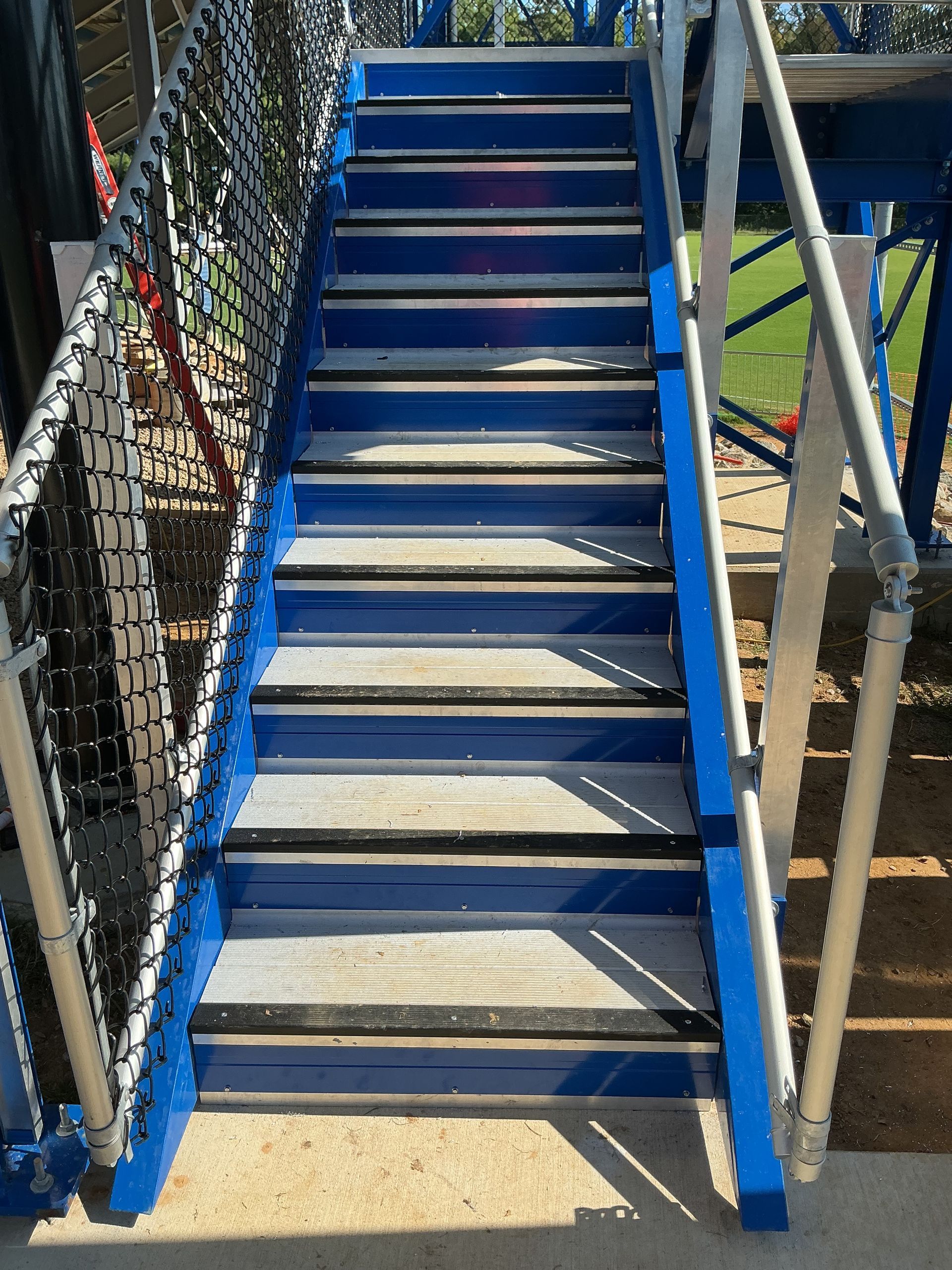 Blue and gray staircase with handrails on either side, leading upwards.