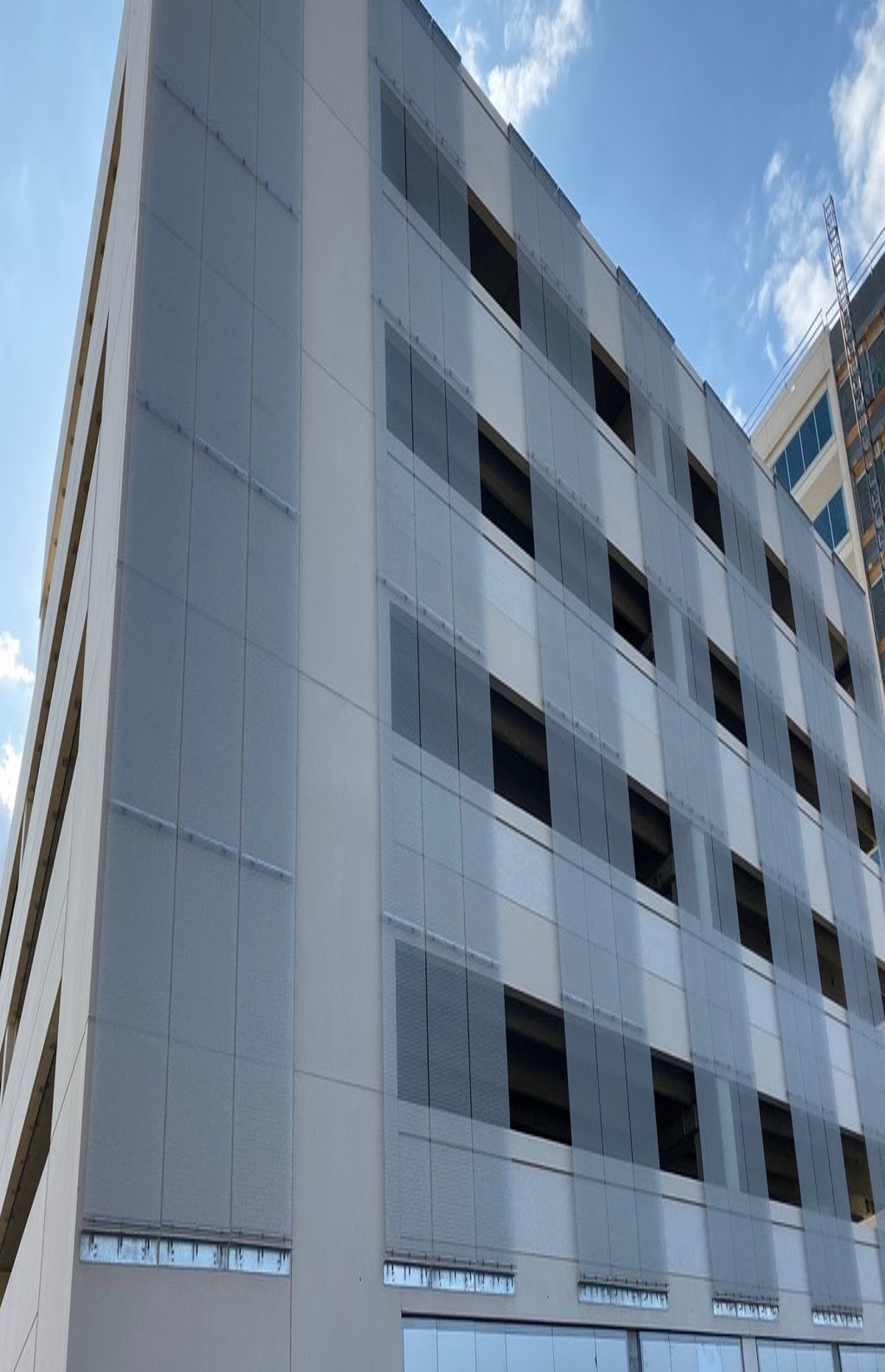 Multi-story modern building with gray and glass facade, blue sky visible.