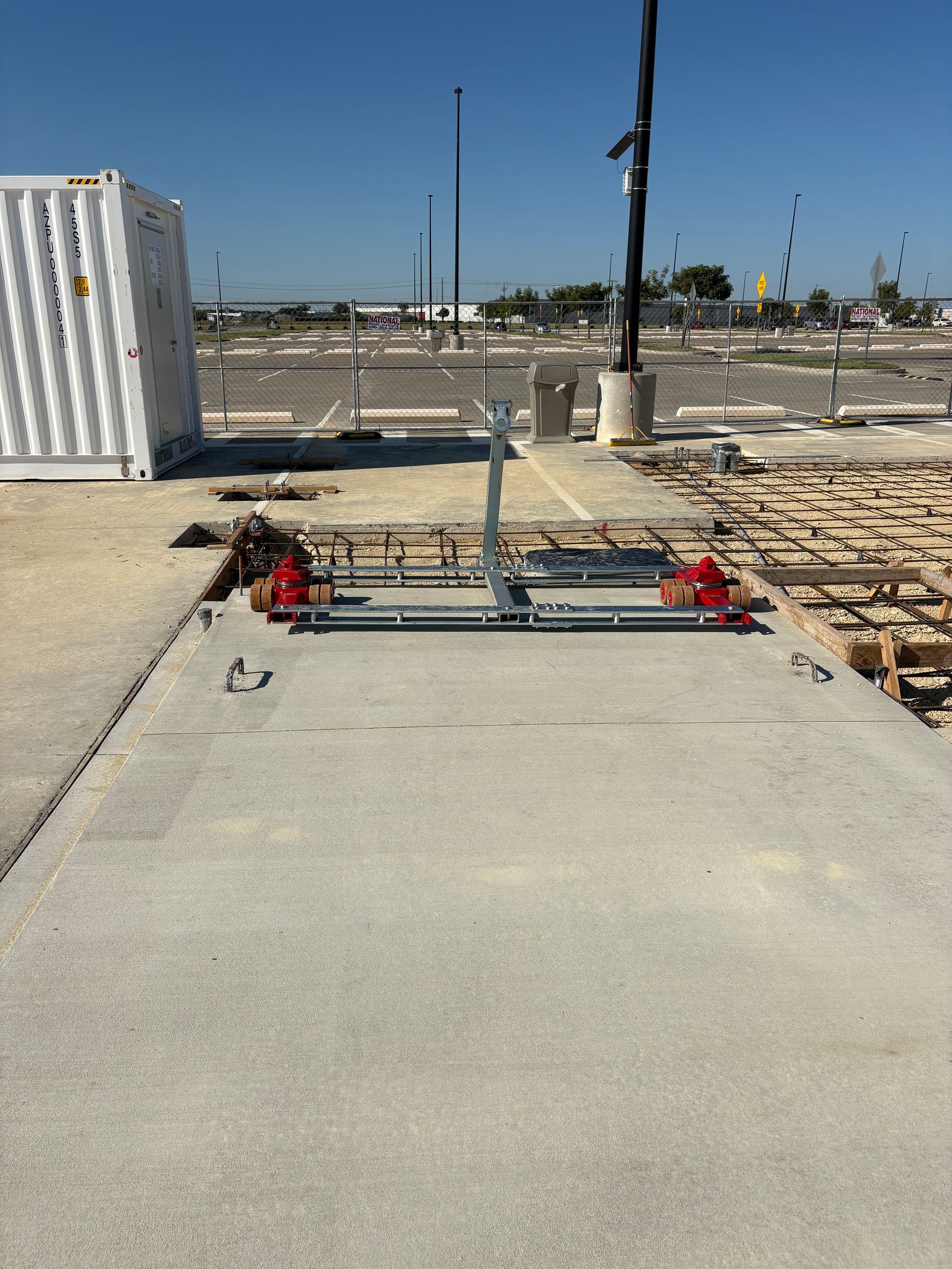 Construction site with a concrete slab, metal scaffolding, and shipping container.