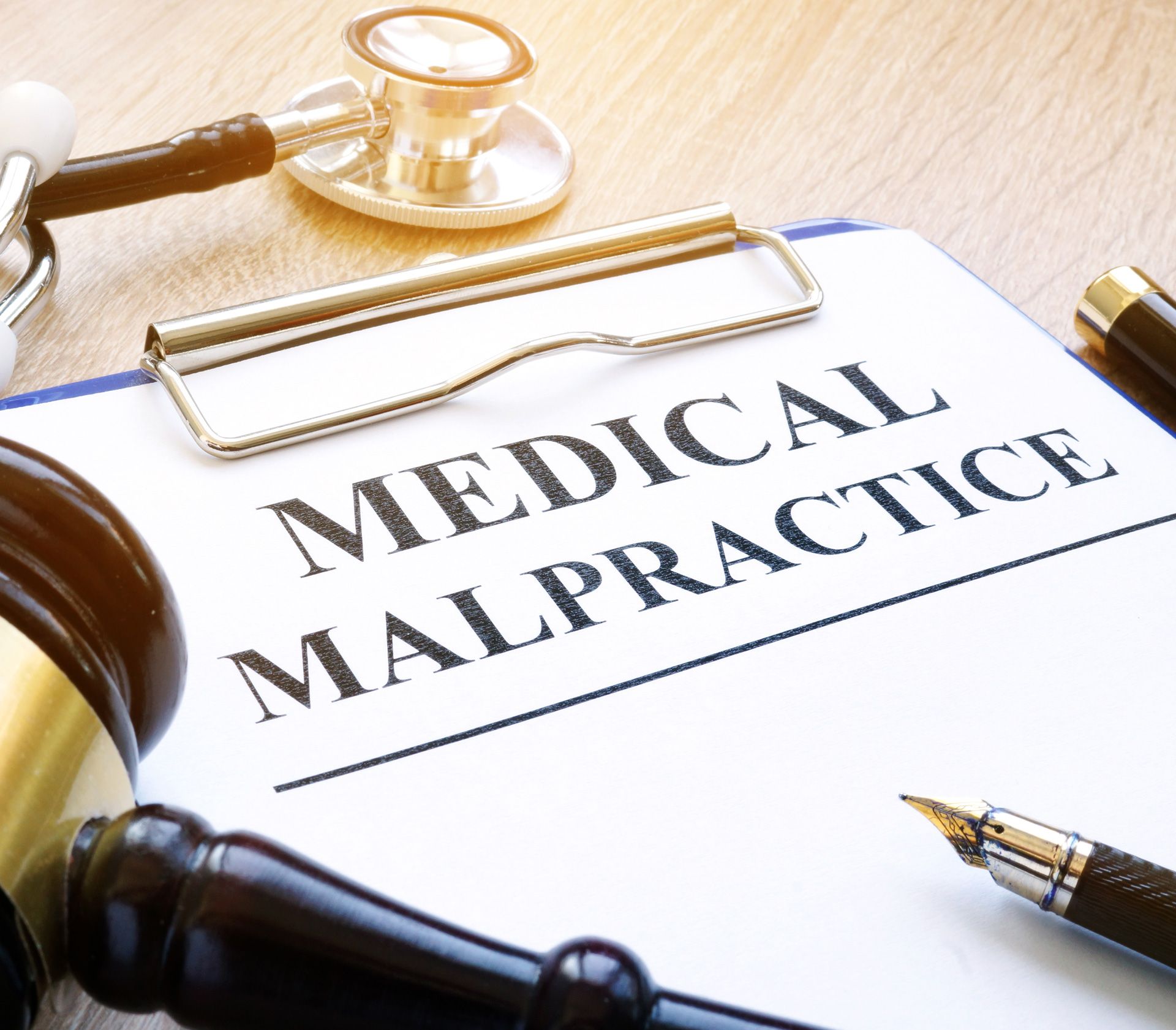 Medical malpractice form with stethoscope, gavel, and pen on a wooden table.