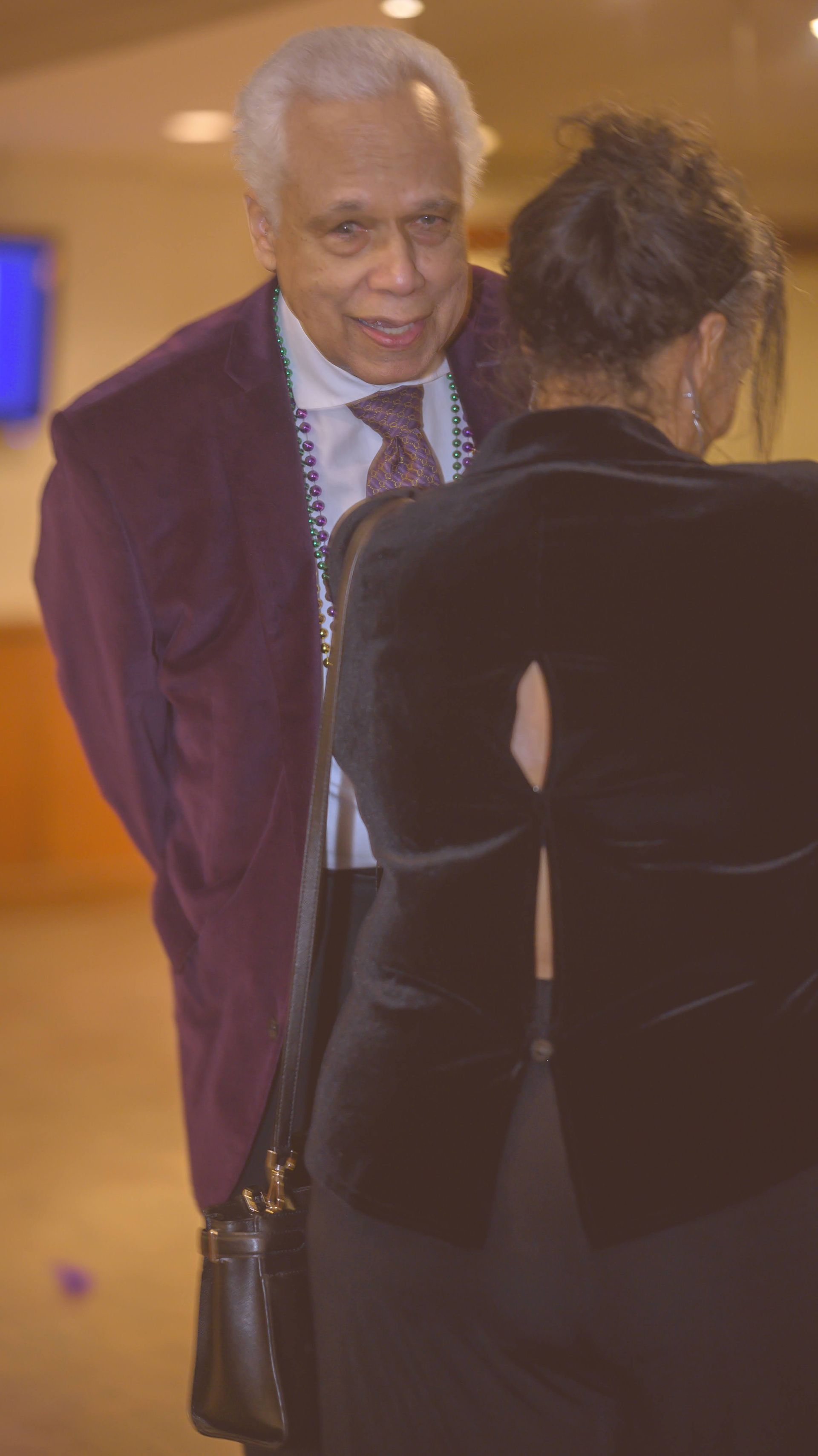 A man in a suit and tie is talking to a woman in a black dress.