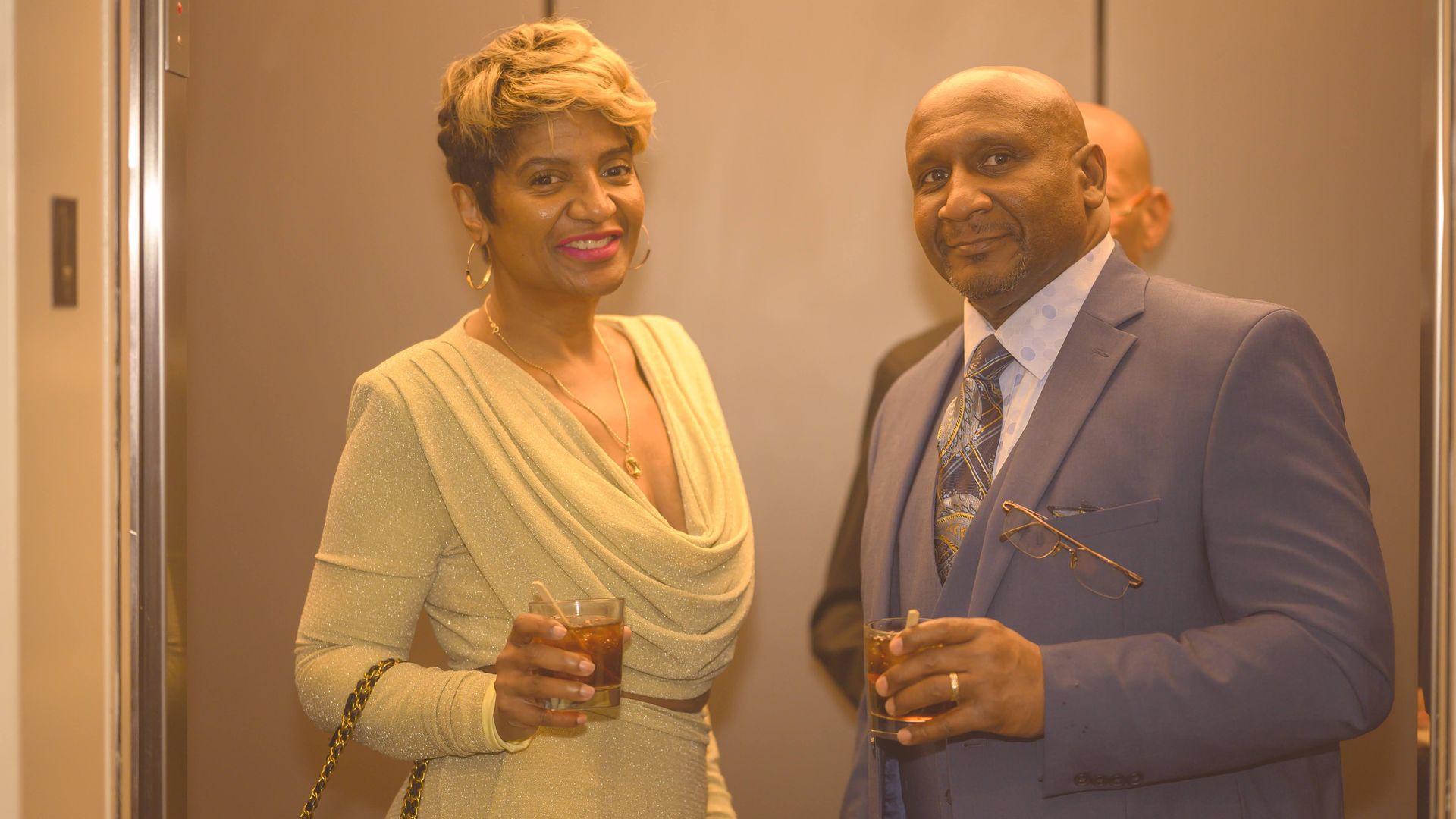 A man and a woman are standing next to each other holding drinks.