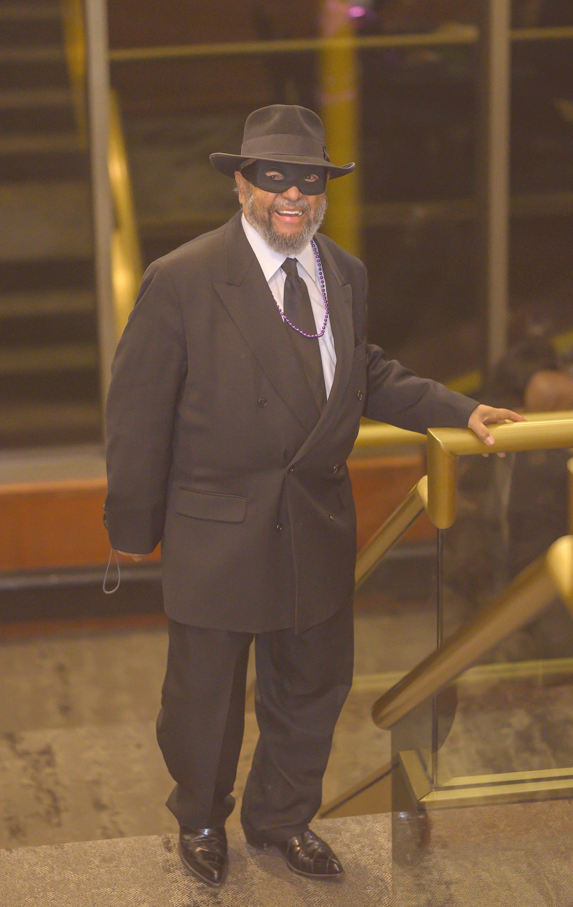 A man in a suit and hat is leaning against a railing
