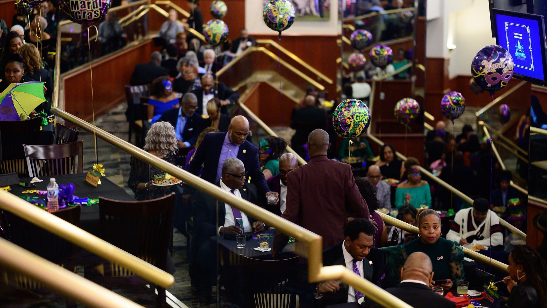 A group of people are sitting at tables in a room with balloons.