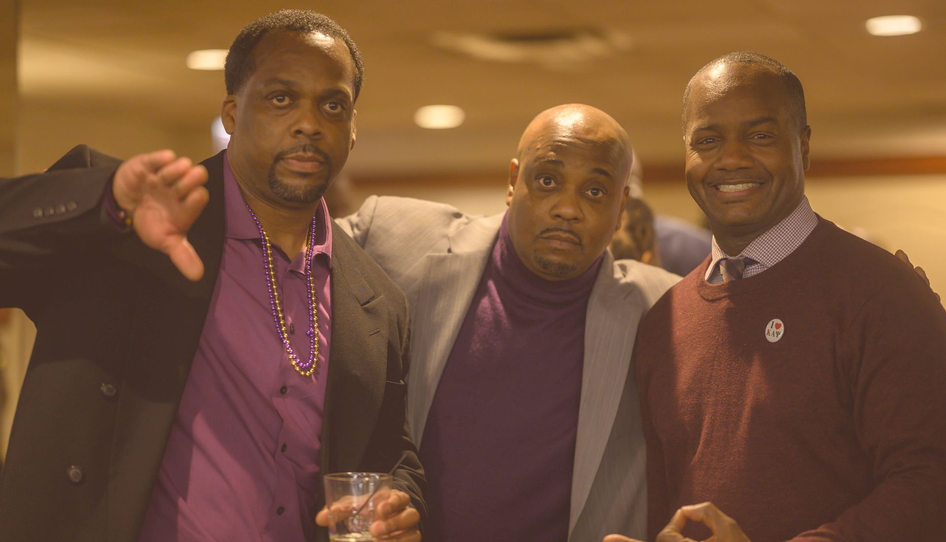 Three men are posing for a picture together and one of them is giving the thumbs down sign.