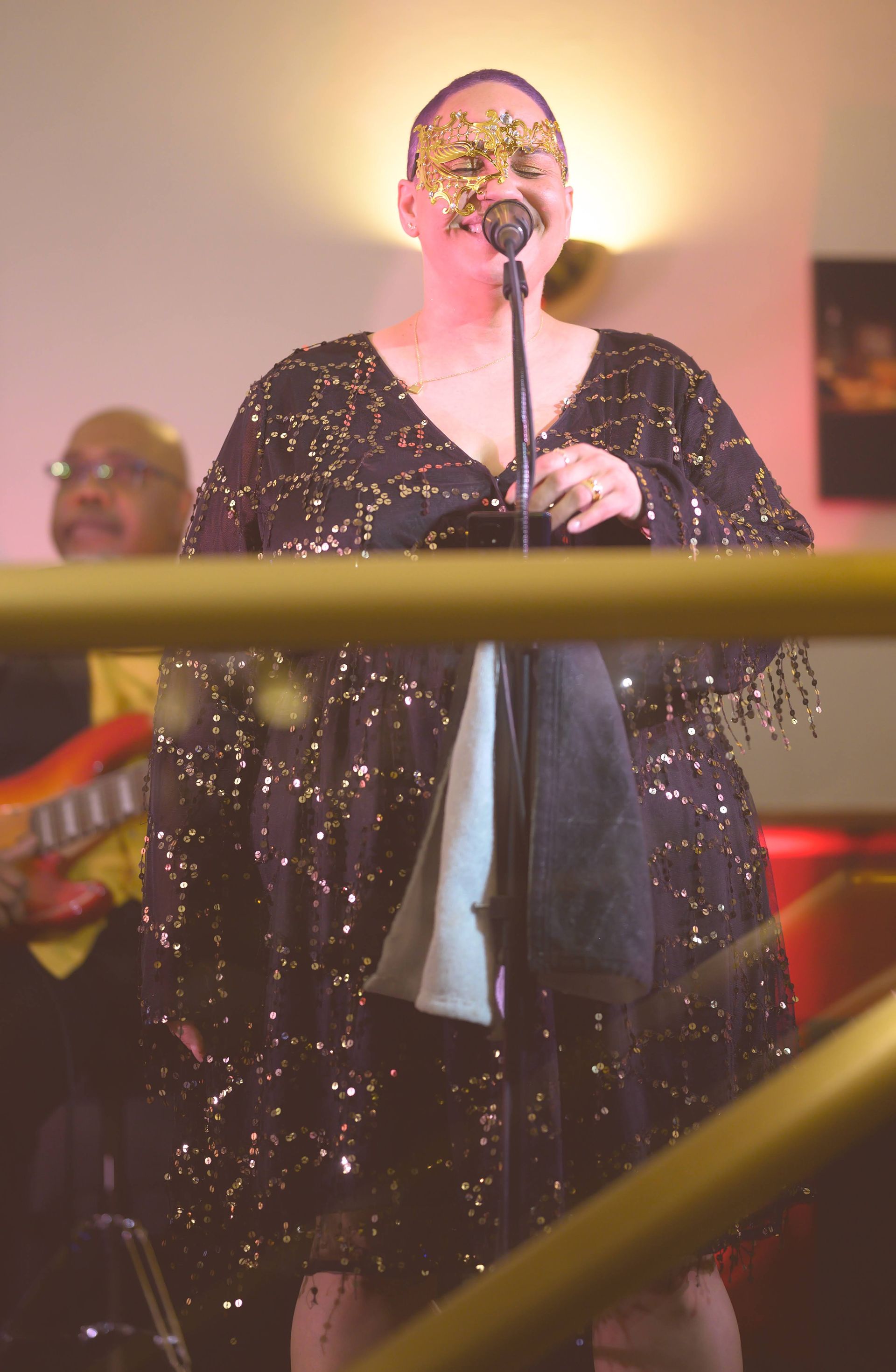 A woman wearing a mask is singing into a microphone.