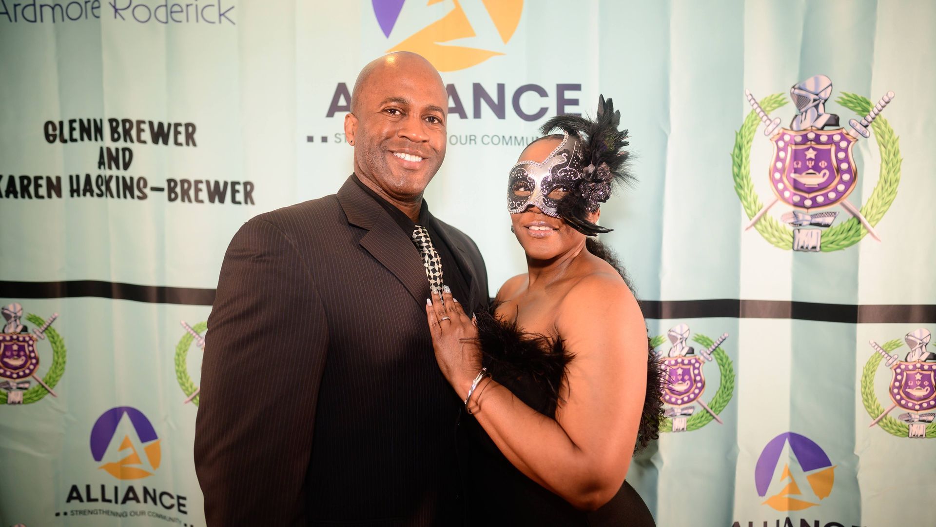 A man and a woman are posing for a picture in front of a banner that says alliance