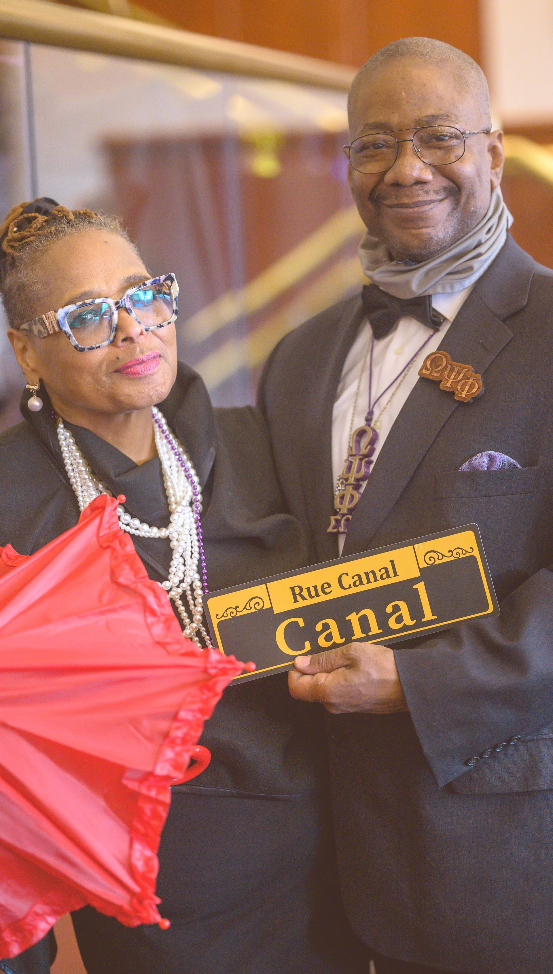 A man and a woman are holding an umbrella and a sign that says canal.