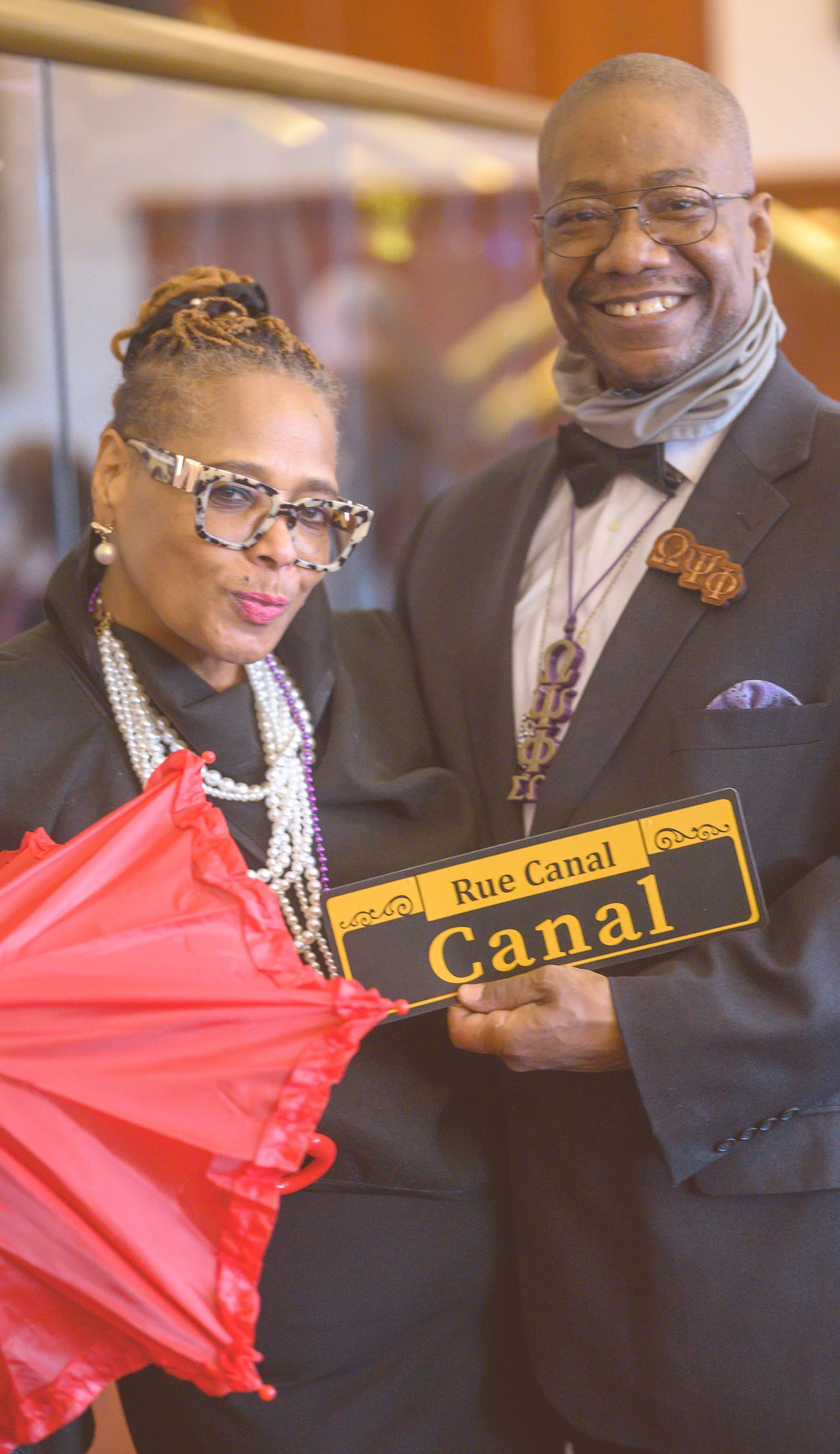 A man and a woman are holding an umbrella and a sign that says canal.