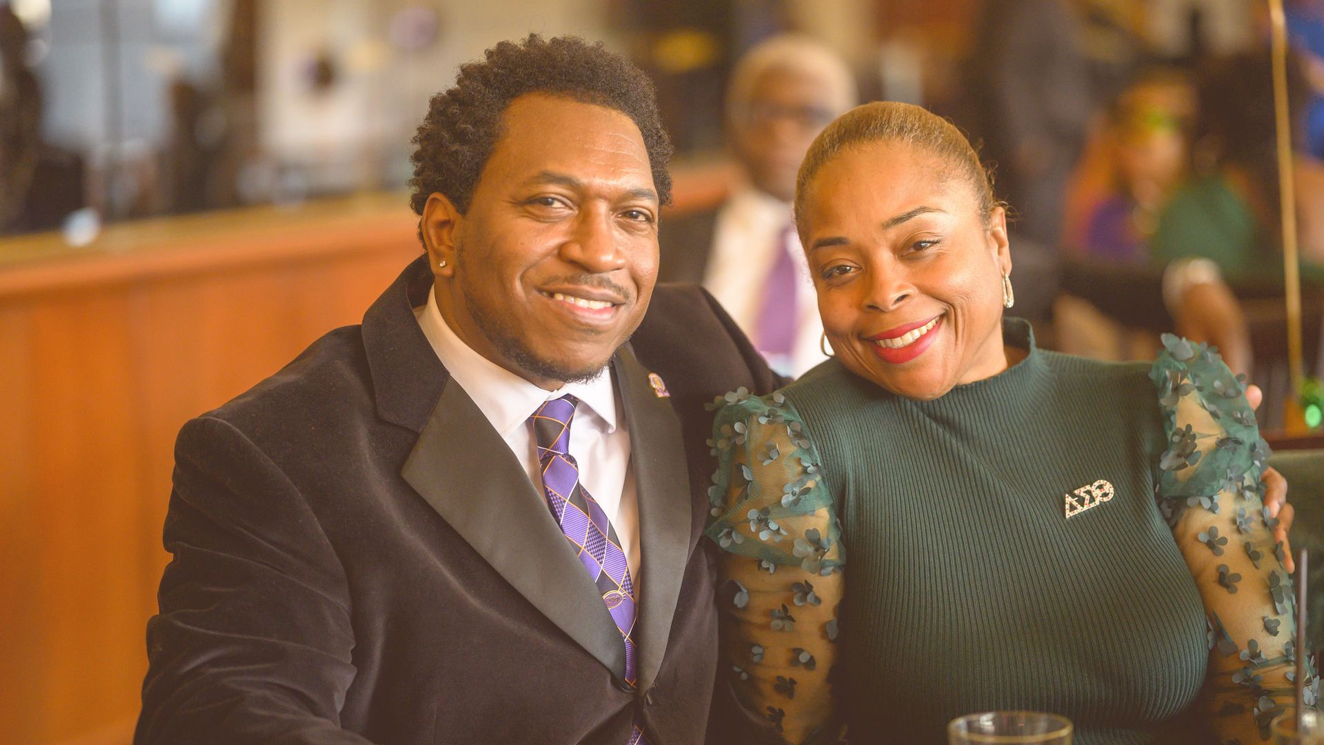 A man and a woman are posing for a picture while sitting at a table.