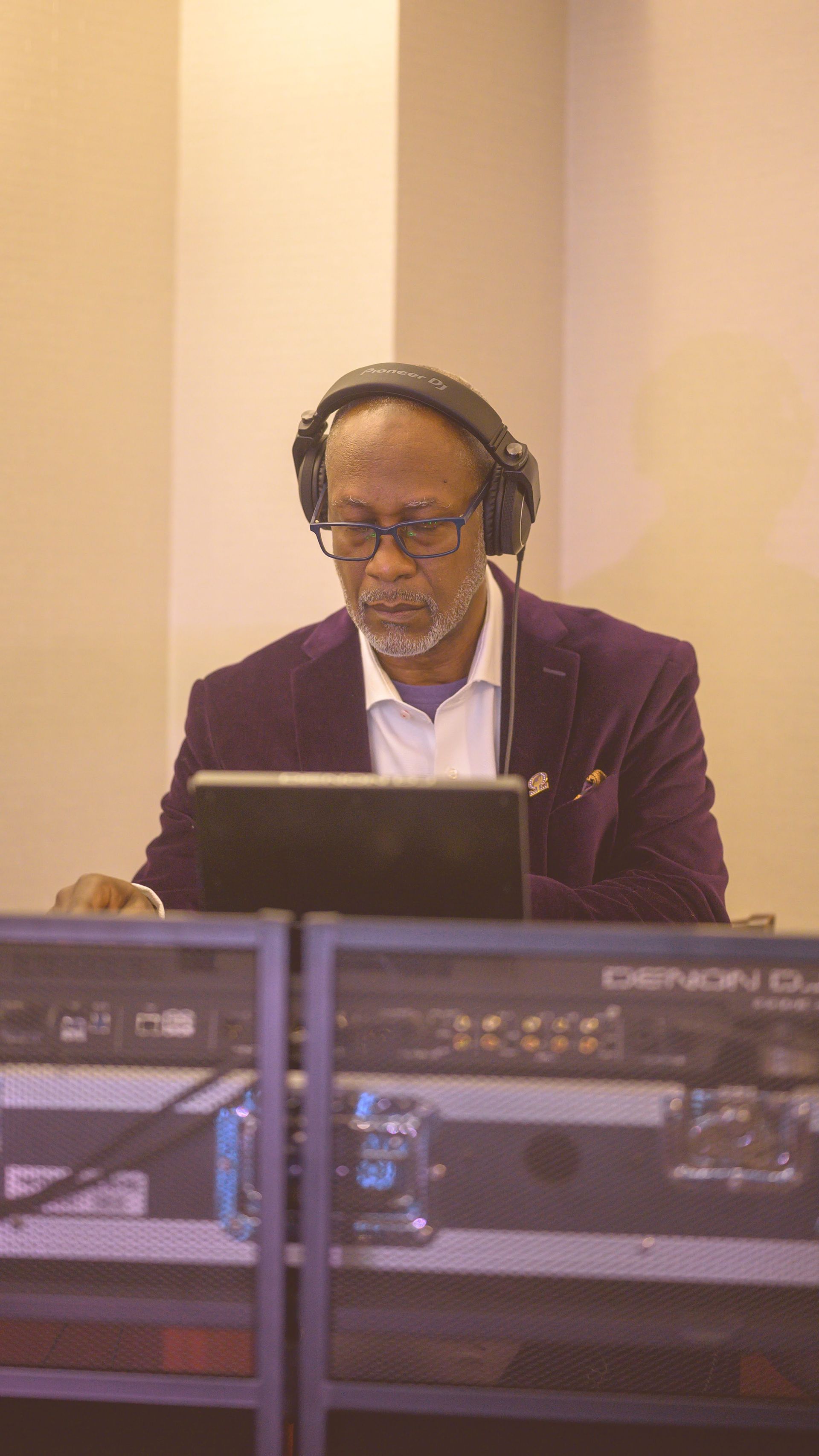 A man wearing headphones is playing music on a laptop computer.