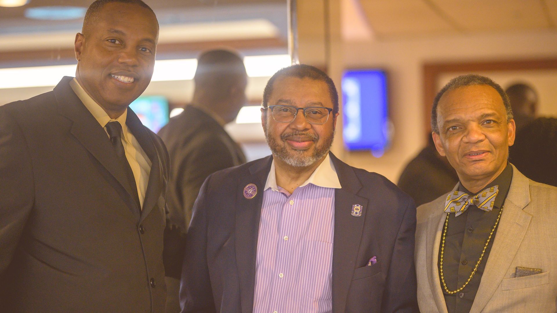 Three men in suits and bow ties are posing for a picture.