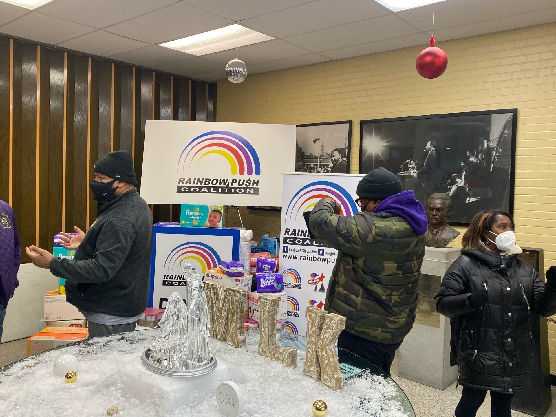 A group of people wearing face masks are standing around a fountain in a room.