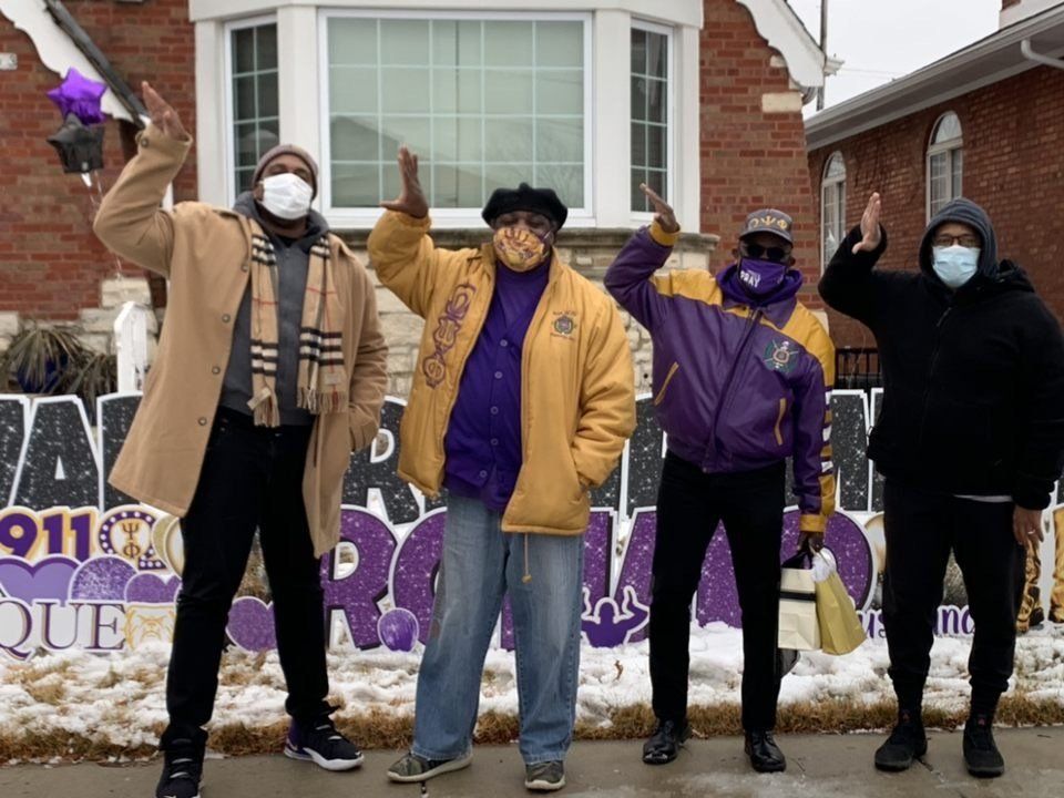A group of men wearing face masks are standing in front of a sign that says 911
