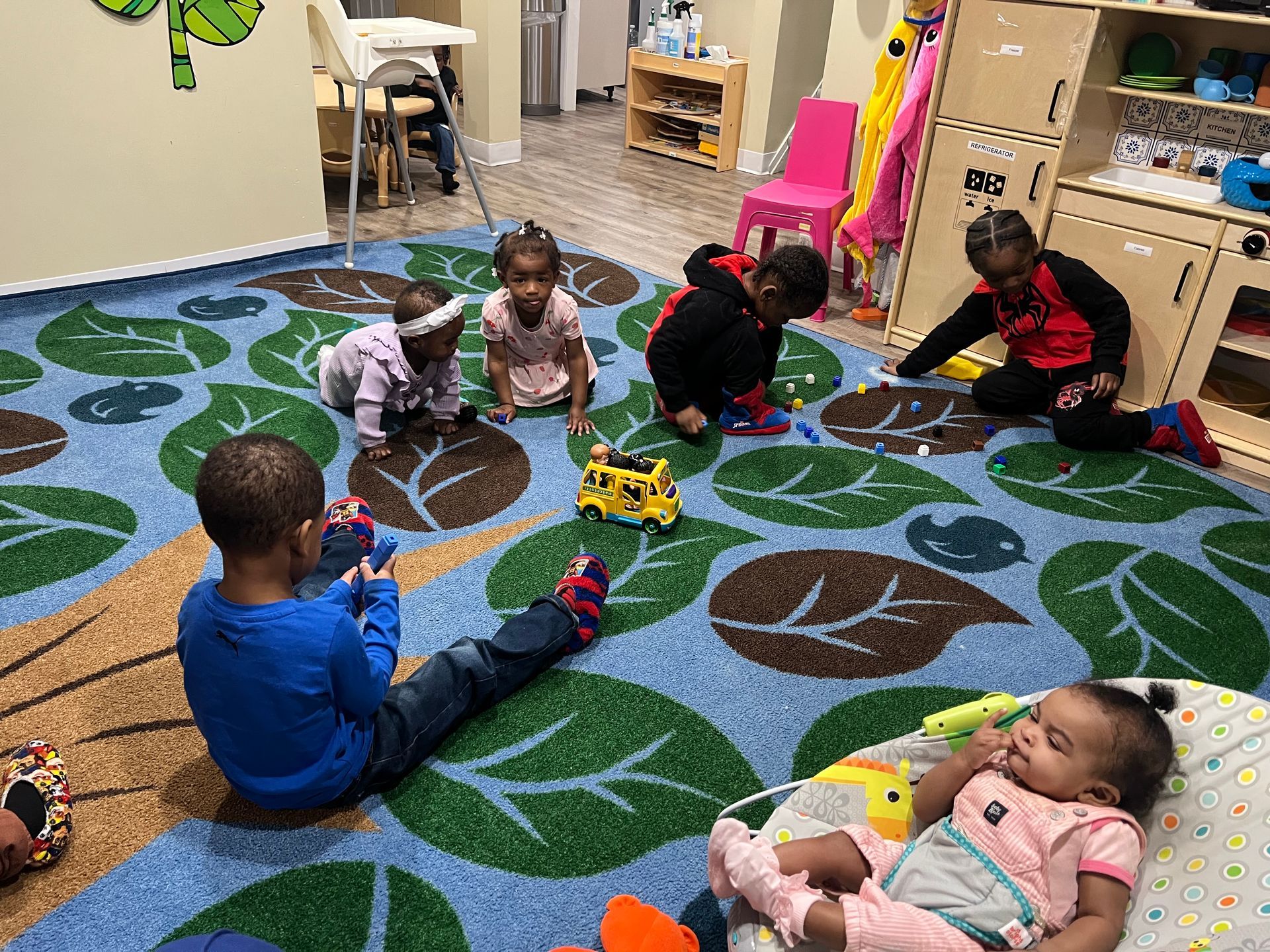 A group of children are sitting on the floor playing with toys.