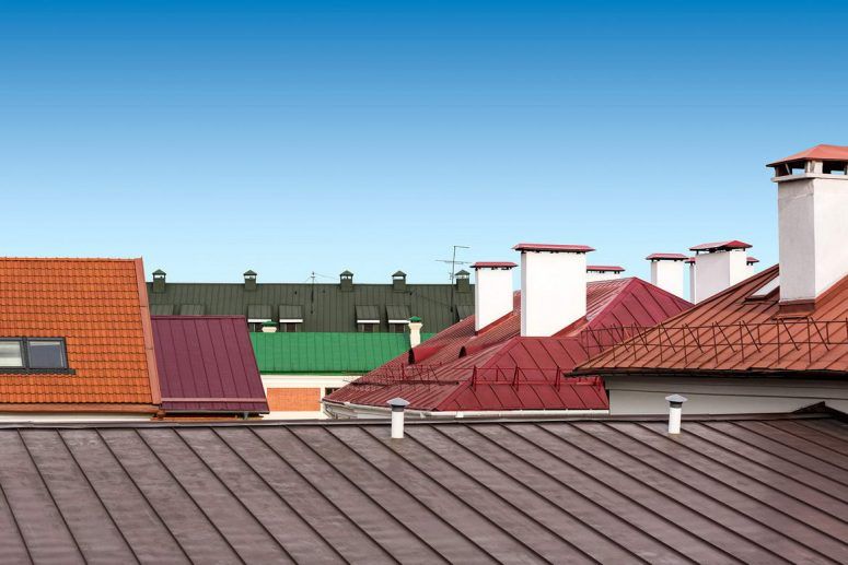 A row of roofs with chimneys and a blue sky in the background.