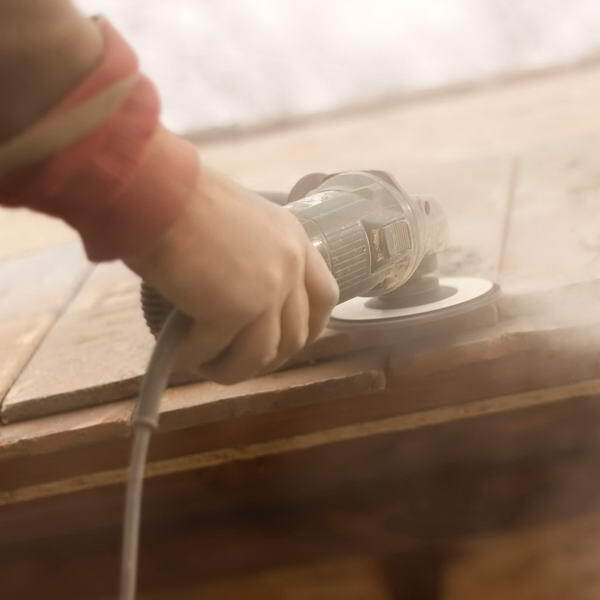 A person is sanding a piece of wood with a grinder.