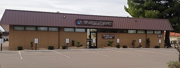 A one-story brick building with a brown roof and a sign reading 
