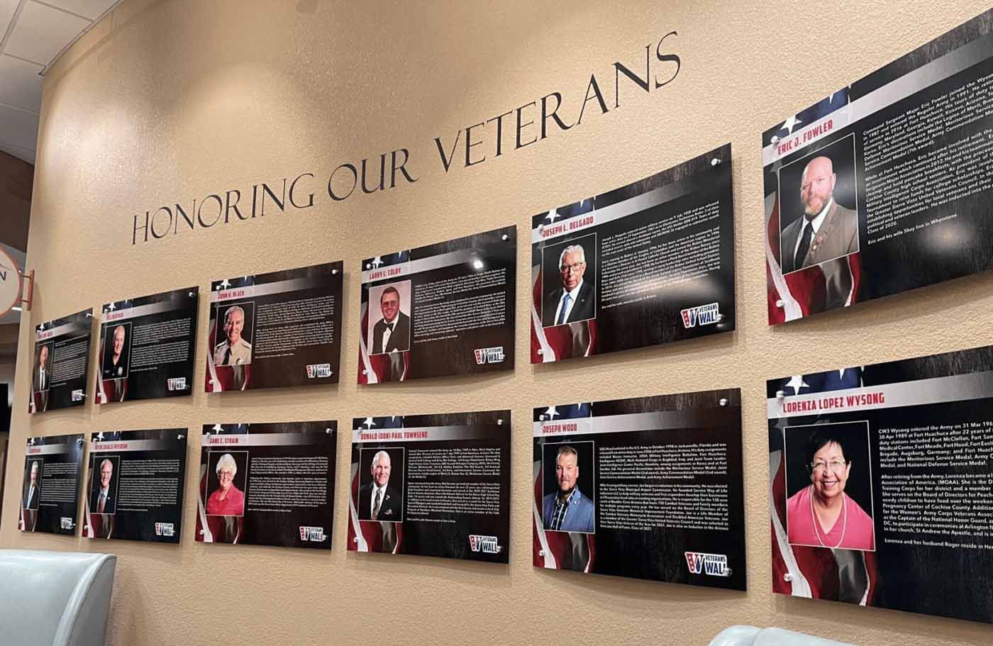 Wall display honoring veterans with photos and text. Cream wall with 