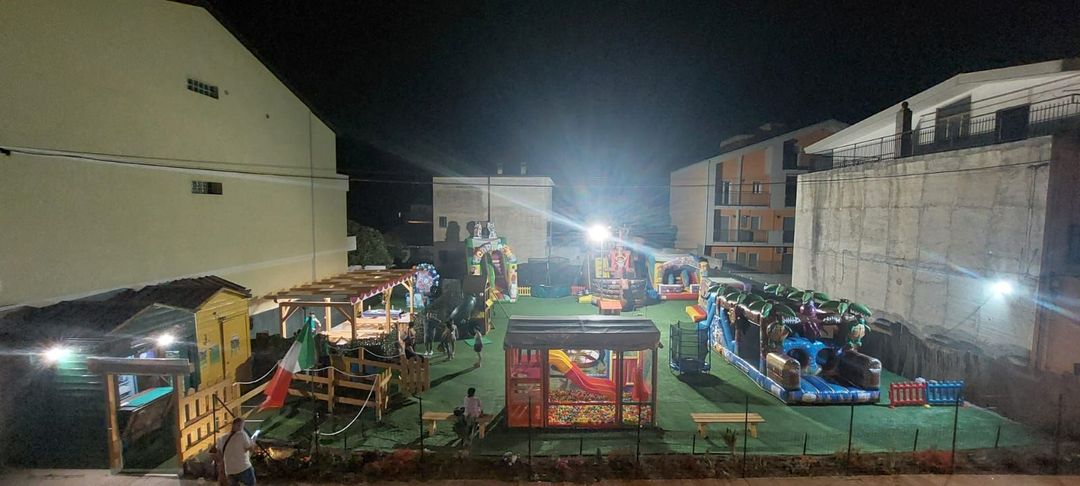 Una veduta aerea di un parco giochi di notte con edifici sullo sfondo.
