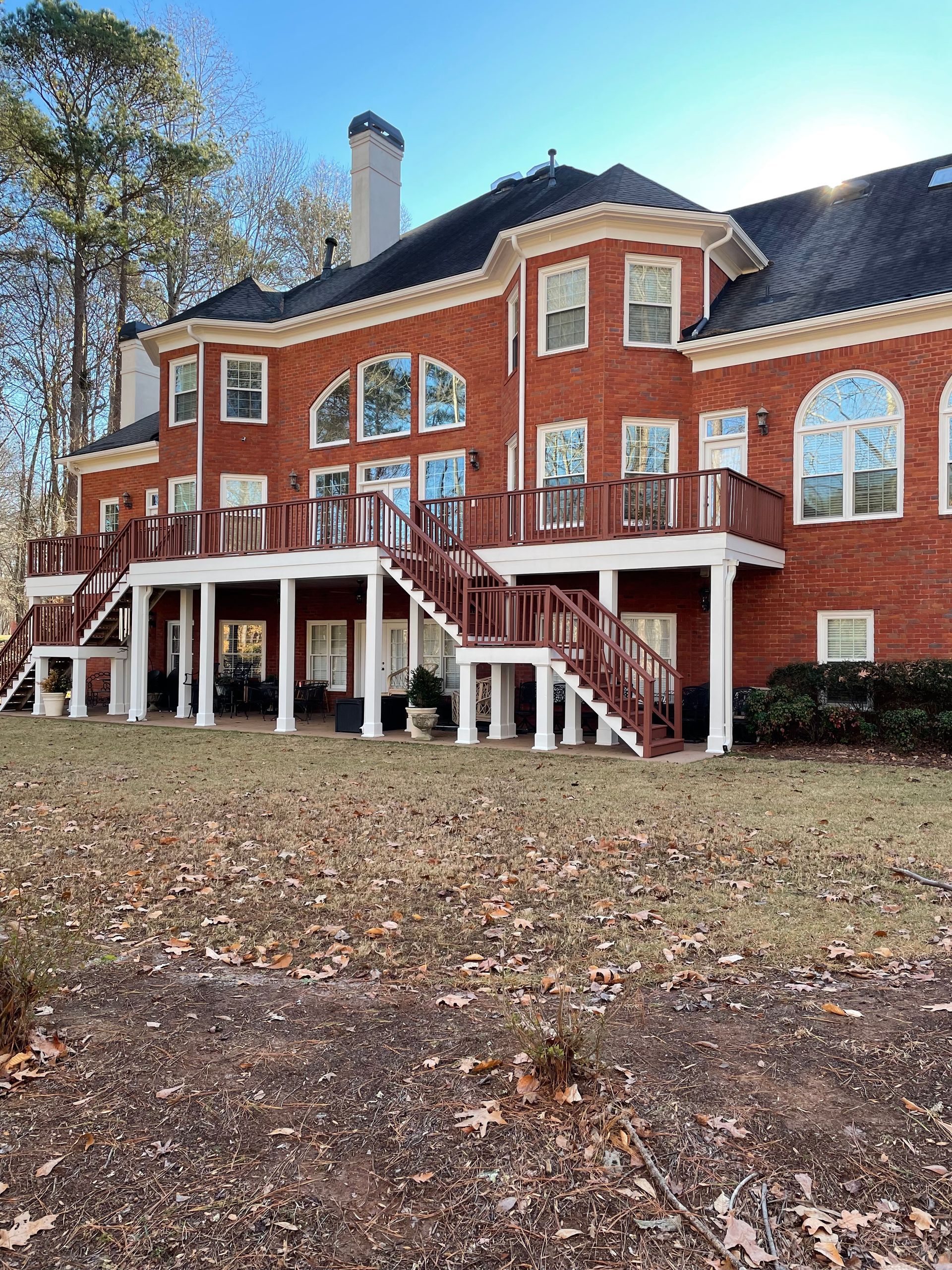 A large brick house with a large deck and stairs.