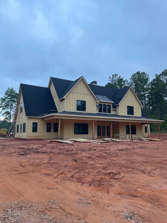 A large house is being built in a dirt field.