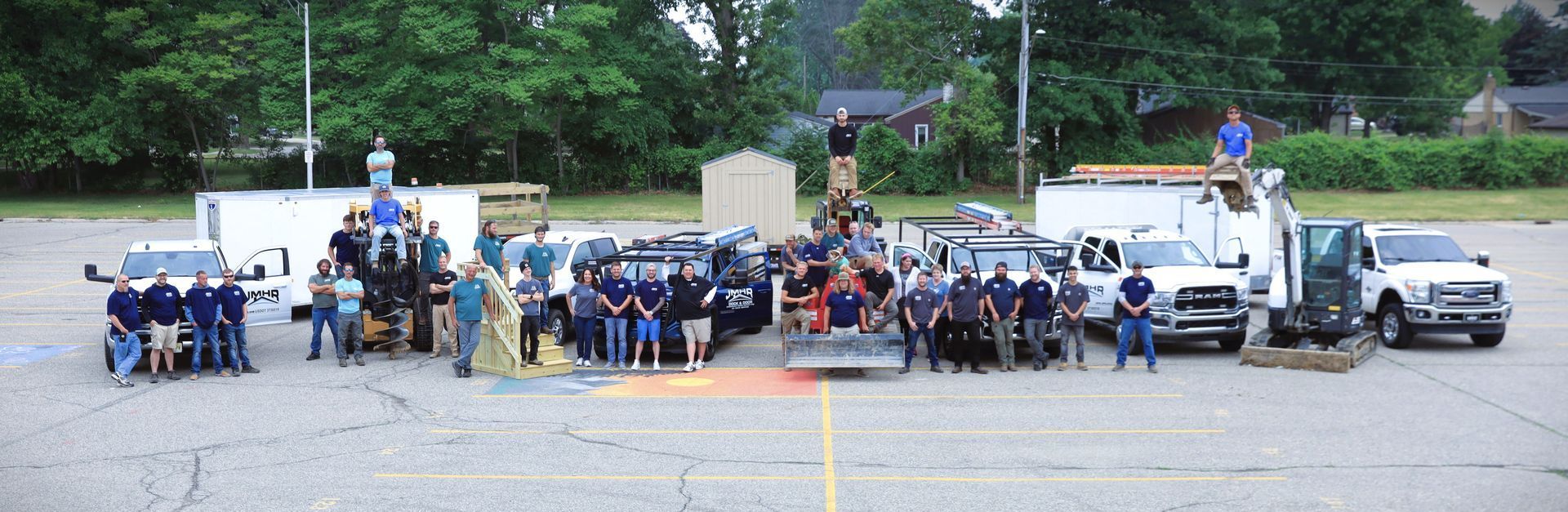 A group of people standing around vehicles and equipment in a parking lot.