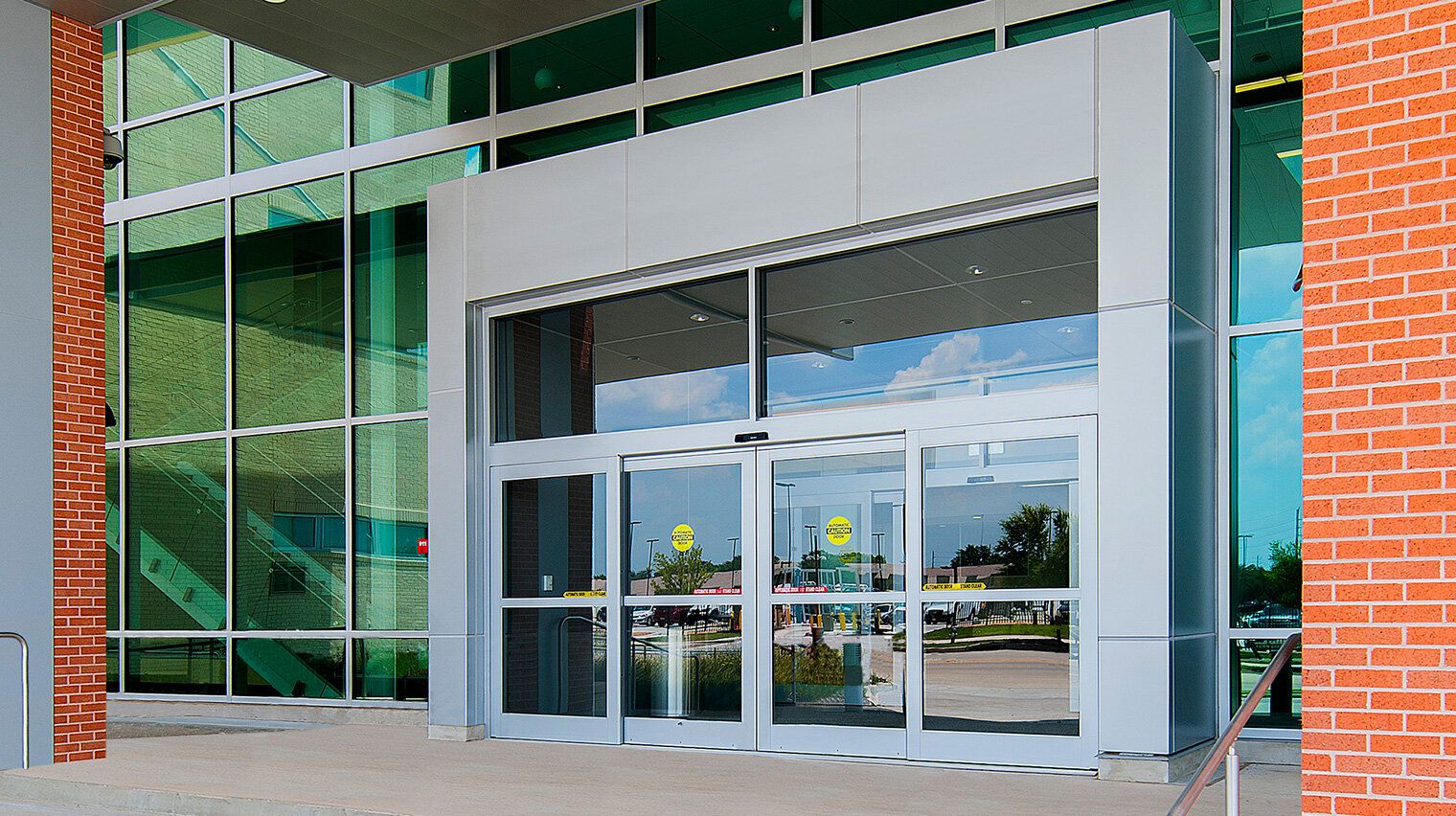 Automatic glass doors at the entrance of a building with brick and glass exterior.