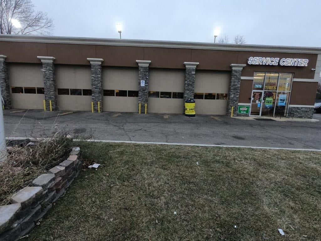 Exterior of a car wash facility with closed garage doors, brown siding, and a convenience store entrance.