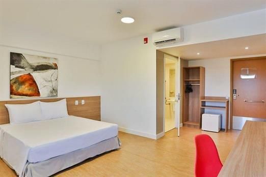 Um quarto de hotel com uma cama, escrivaninha e cadeira