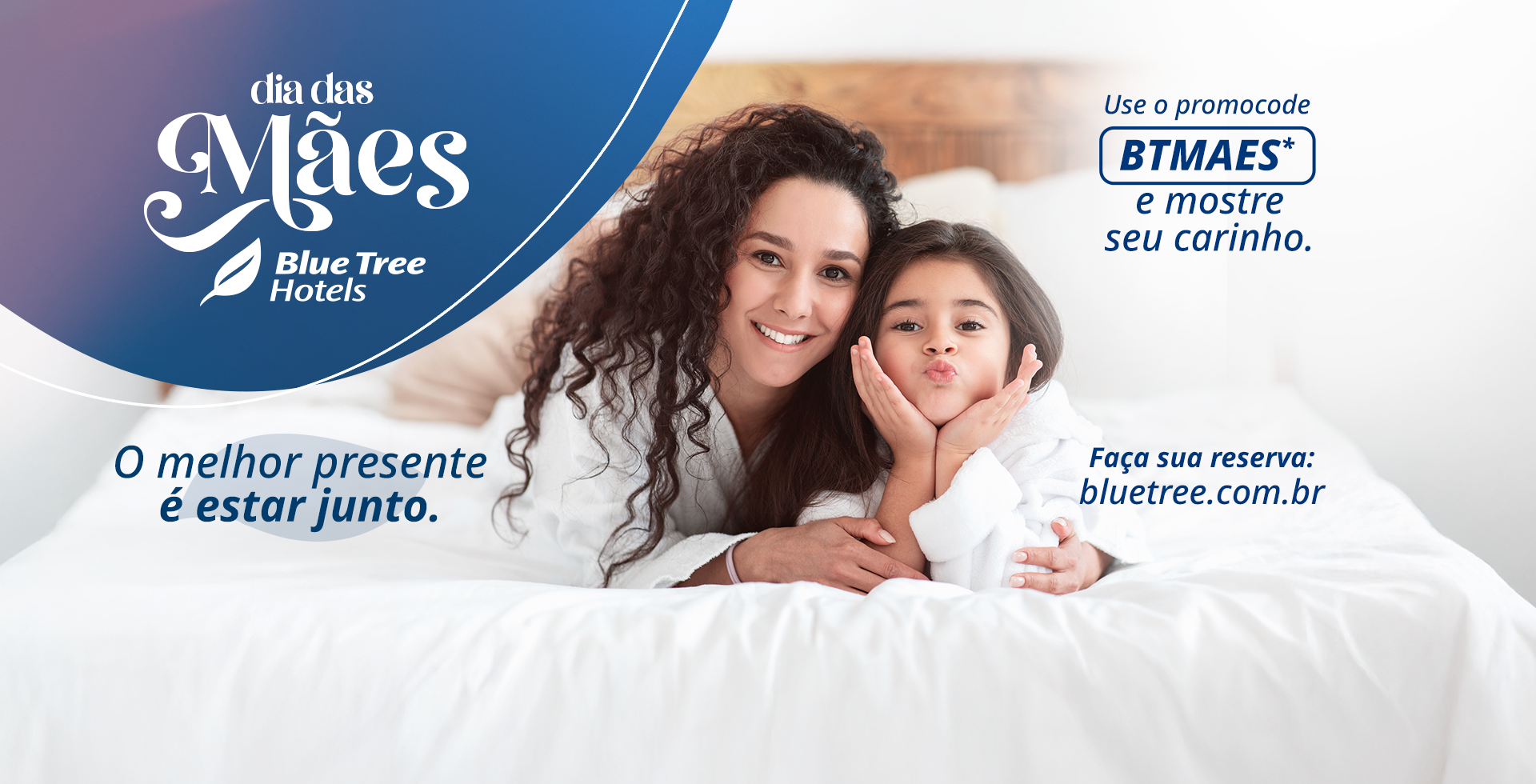 Uma mulher e um bebê estão enrolados em toalhas e deitados em uma cama.