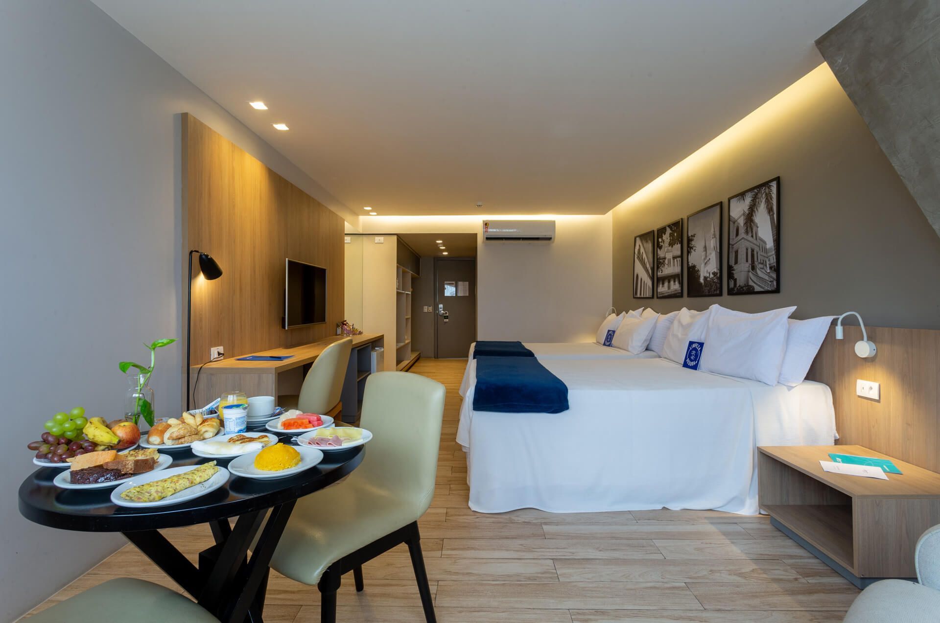 Um quarto de hotel com duas camas e uma mesa com comida.