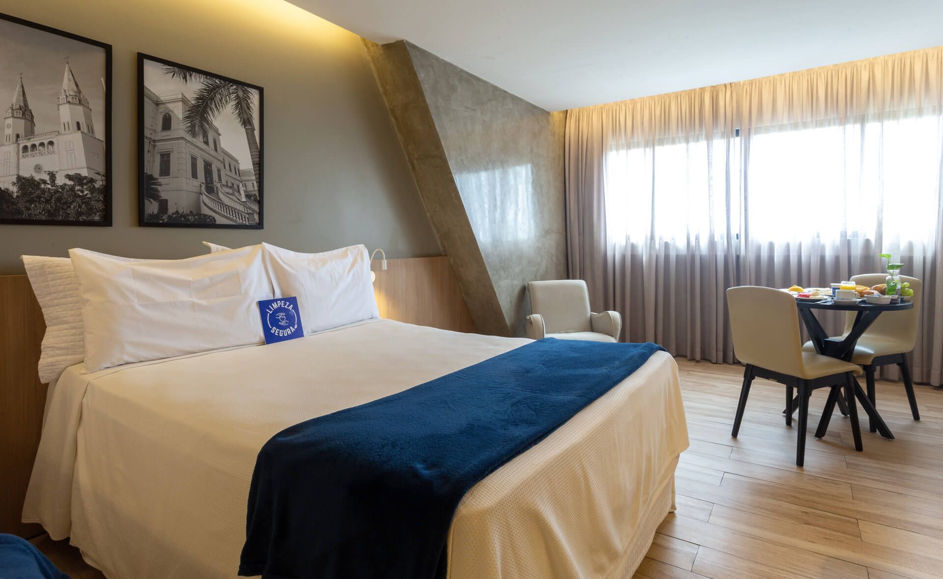 Um quarto de hotel com uma cama king size, uma mesa e cadeiras.