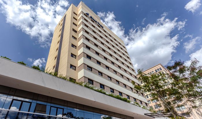 Um grande edifício com muitas janelas contra um céu azul com nuvens.