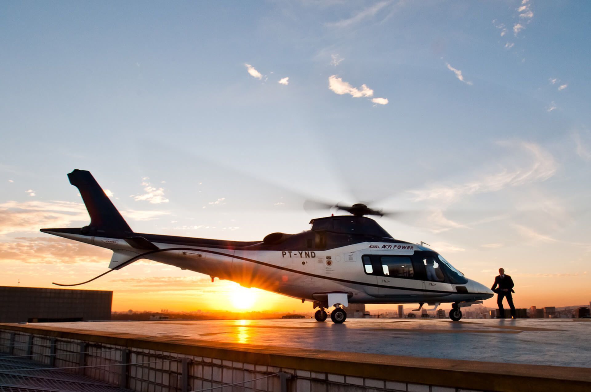 Um helicóptero está estacionado em uma pista ao pôr do sol.