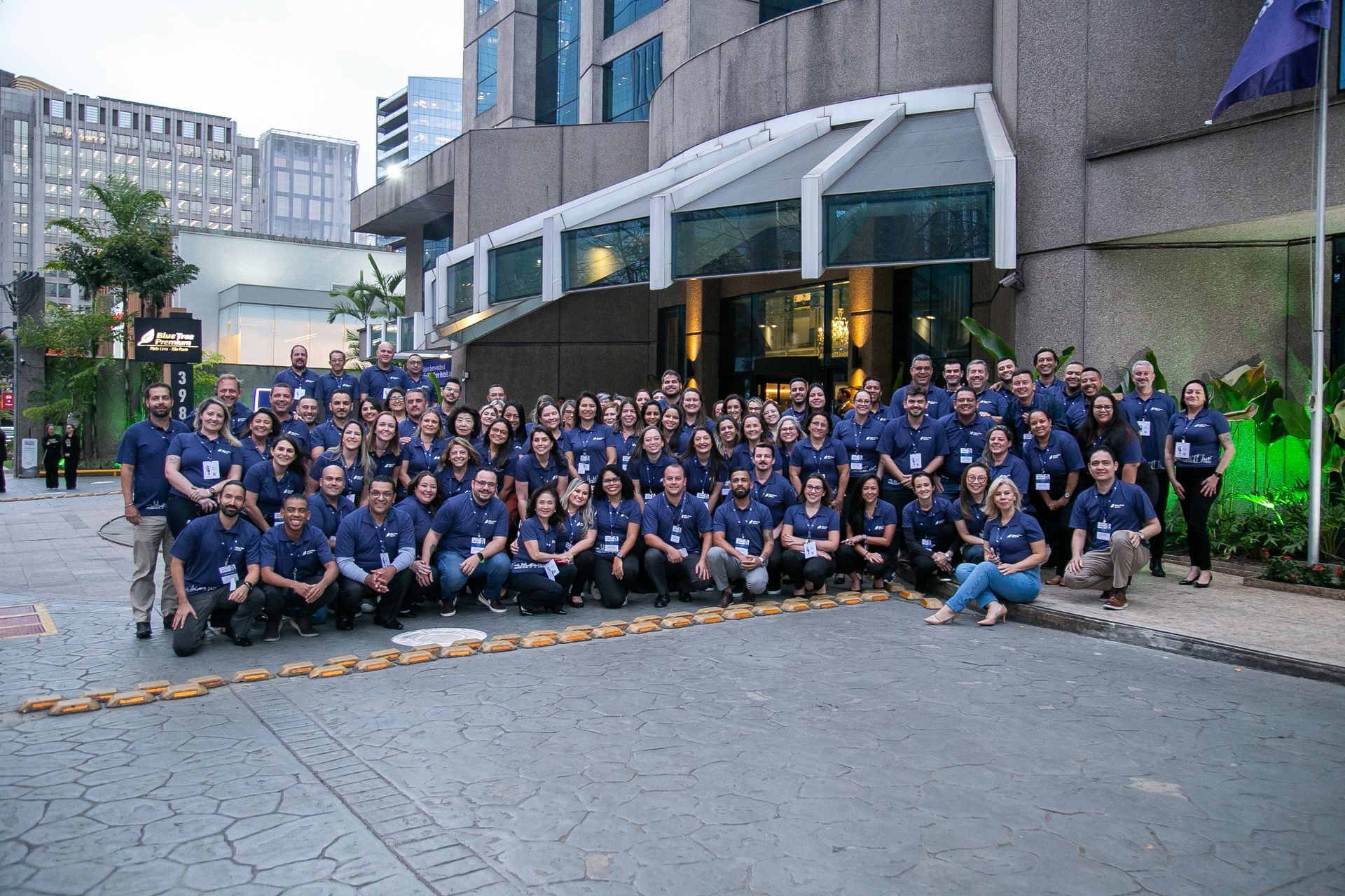 Um grande grupo de pessoas está posando para uma foto em frente a um prédio.