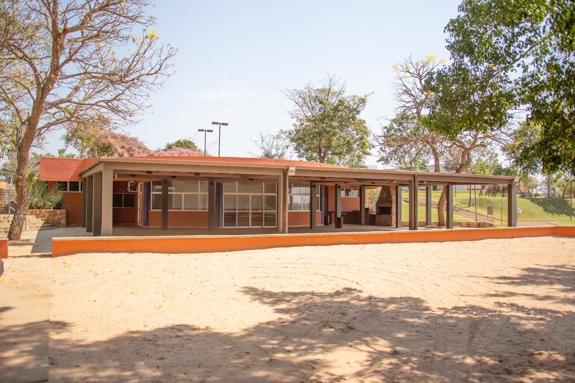 Um grande edifício com telhado vermelho cercado por árvores e areia.