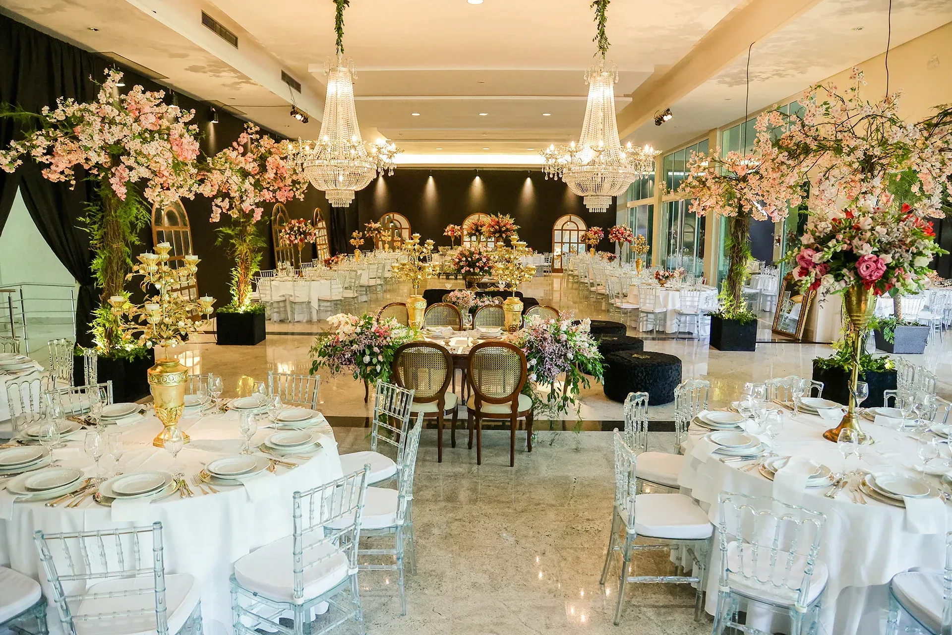 Uma grande sala com mesas e cadeiras preparadas para uma recepção de casamento.