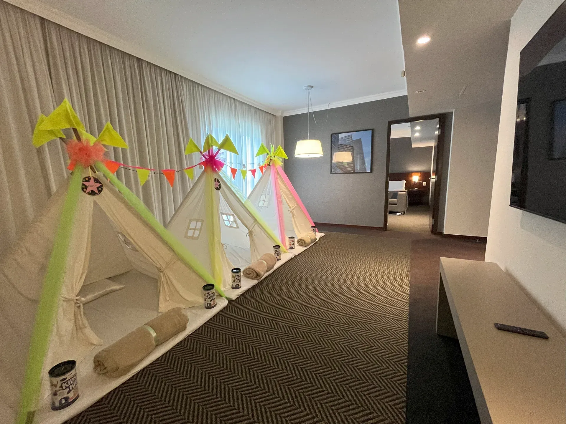 Um quarto de hotel com uma mesa de jantar, cadeiras, um sofá e um espelho.