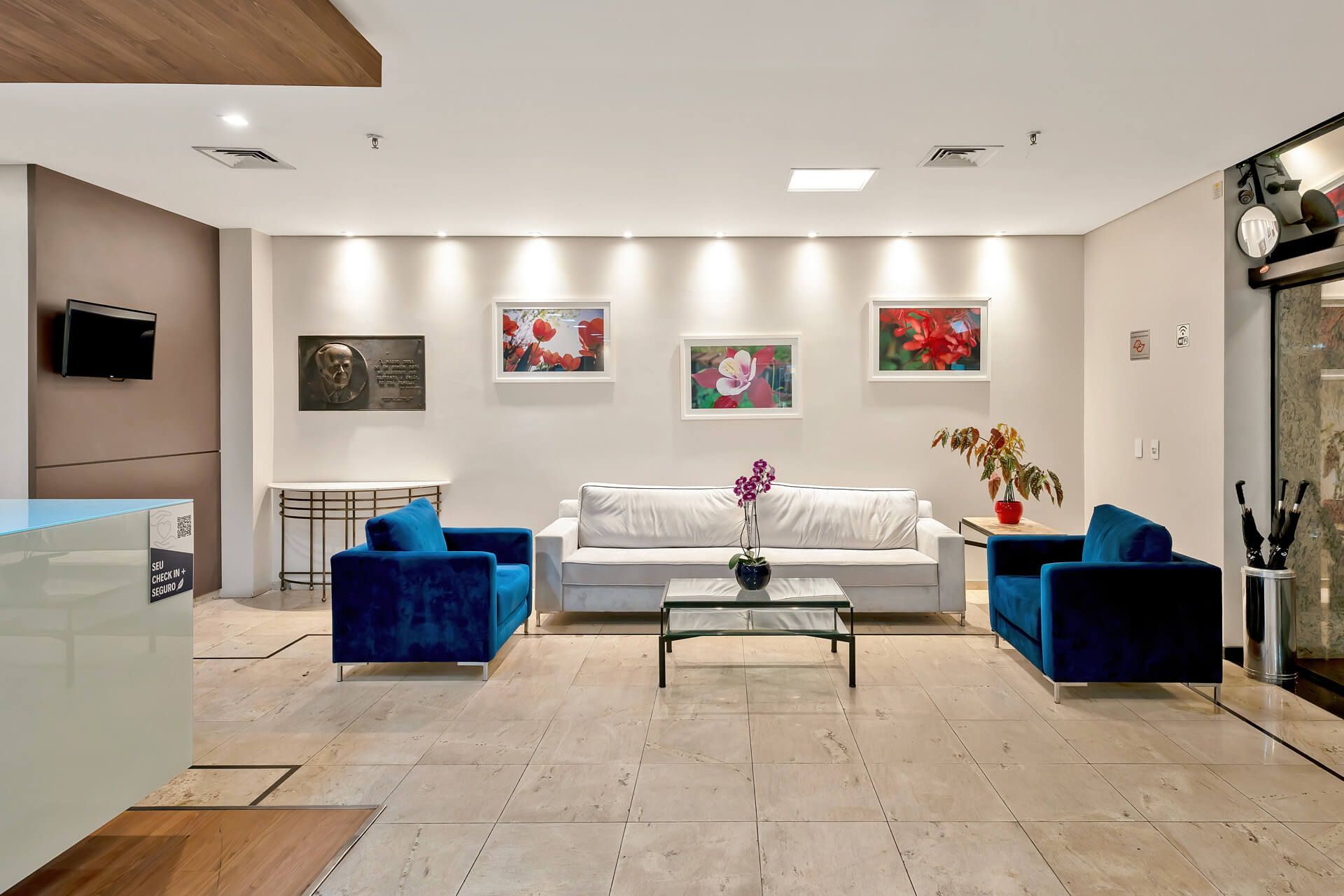 Uma sala de estar com um sofá, duas cadeiras, uma mesa e uma televisão.