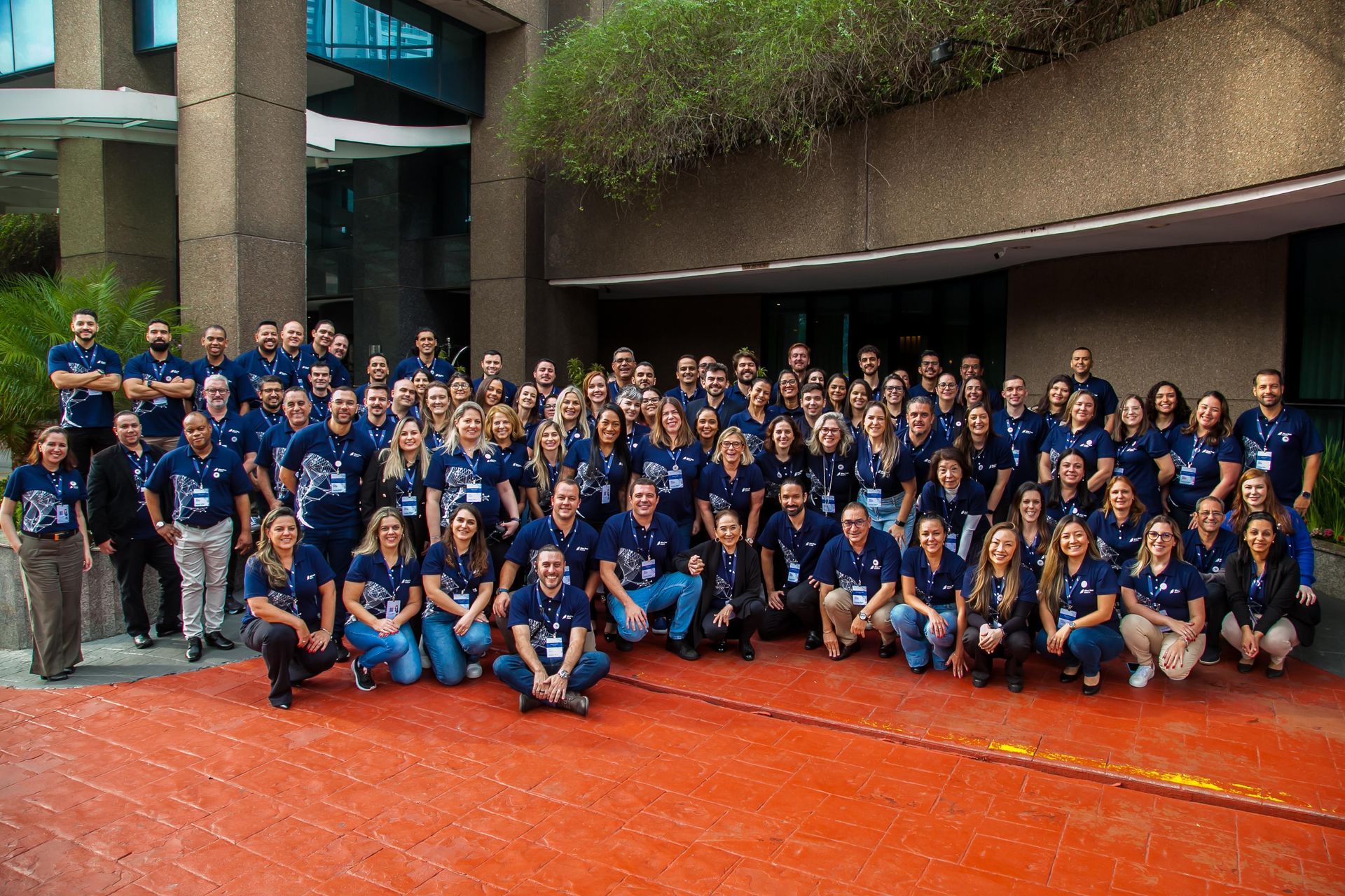 Um grande grupo de pessoas está posando para uma foto em frente a um prédio.