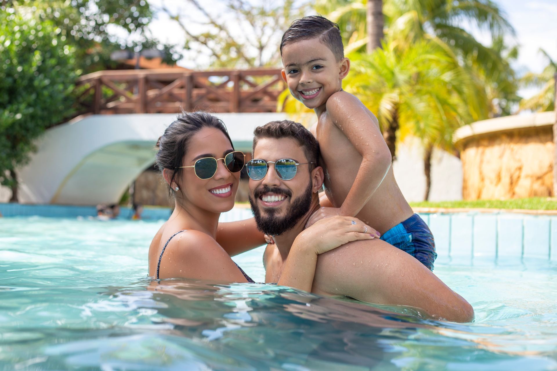 Um homem e uma mulher estão segurando uma criança nos ombros em uma piscina.