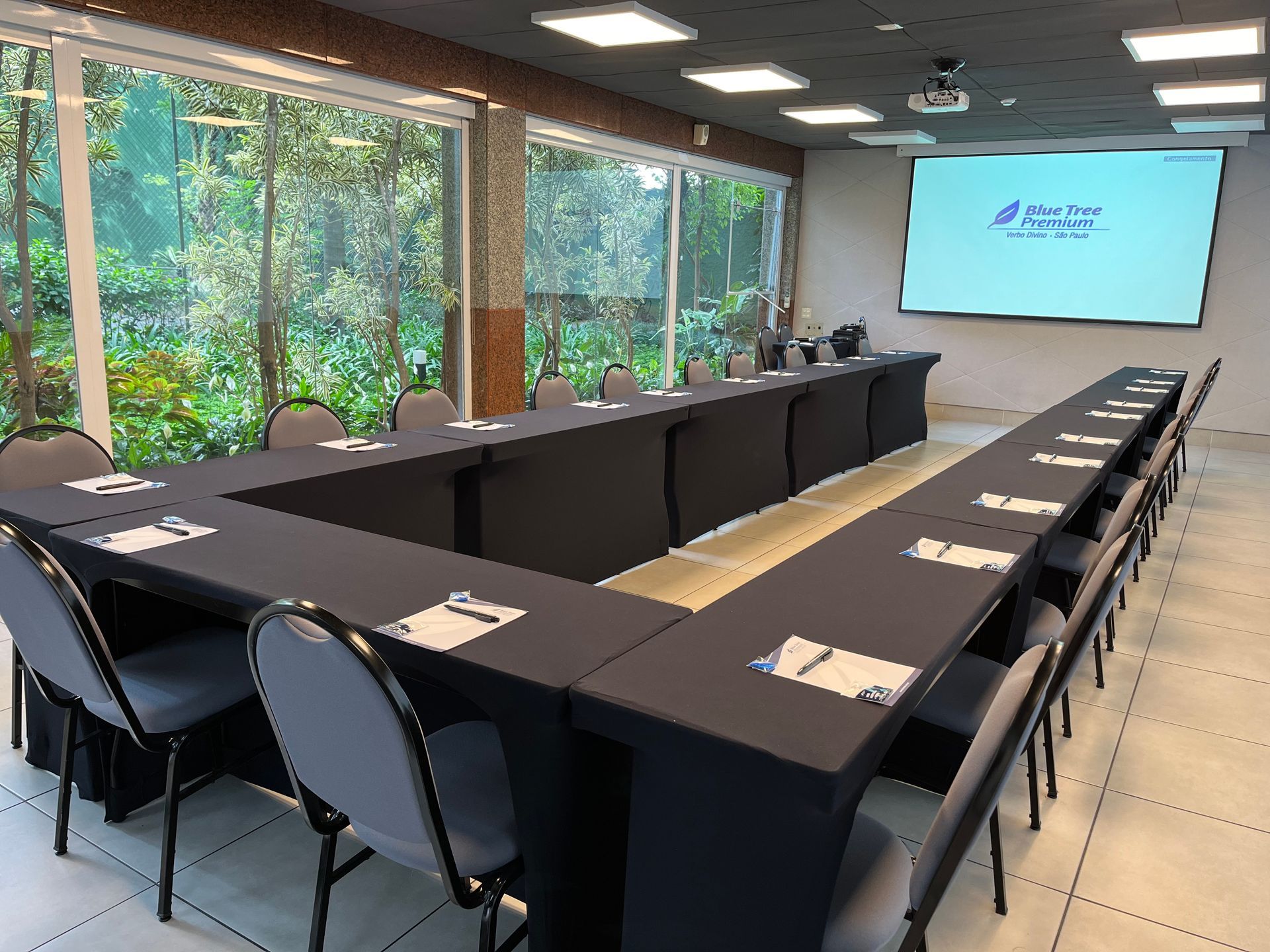 Uma sala de conferências com mesas e cadeiras e uma tela grande.